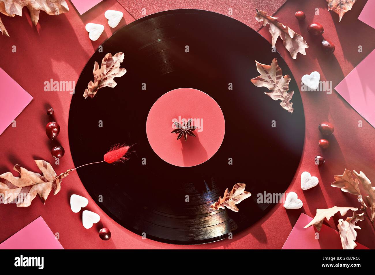Vintage Vinyl Schallplatten in Papierärmel auf schwarzem Hintergrund und Papierärmel. Gelbe Eichenblätter auf rotem Hintergrund mit Herbstverzierungen. Zucker Stockfoto