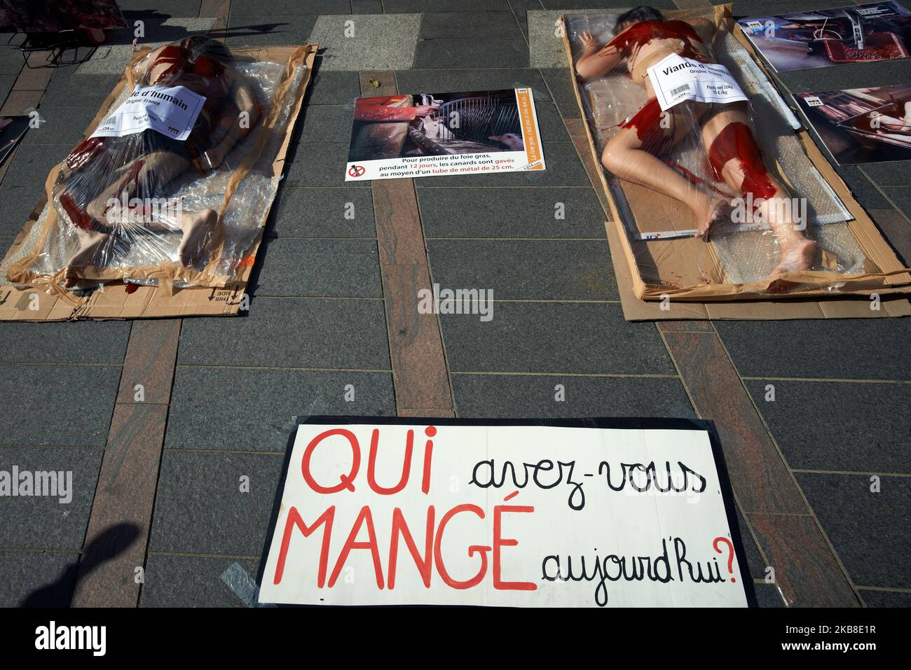 Auf einem Plakat steht: „Wer hast du heute gegessen?“ in der Nähe von zwei Personen, die mit Flaseblut in Schrumpffolien bedeckt sind. Demonstranten des Vereins L214 machten in Toulouse ein Ereignis, um auf den Fleischkonsum aufmerksam zu machen: Etwa L214 Mitglieder stemmten sich in ein in Schrumpffolie verpacktes Tablett und wurden mit falschem Blut mit einem Aufkleber mit der Aufschrift „Human Meat, France Origine“ bedeckt. Der Verein aus dem Jahr L214 wurde berühmt für seine zahlreichen Filme, die in Schlachthöfen gedreht wurden. Ihre Filme zeigten Folter und Missbrauch von Vieh in einigen Schlachthöfen. Toulouse. Frankreich. Oktober 16. 2019. (Foto von Alain Pitton/NurPhoto) Stockfoto