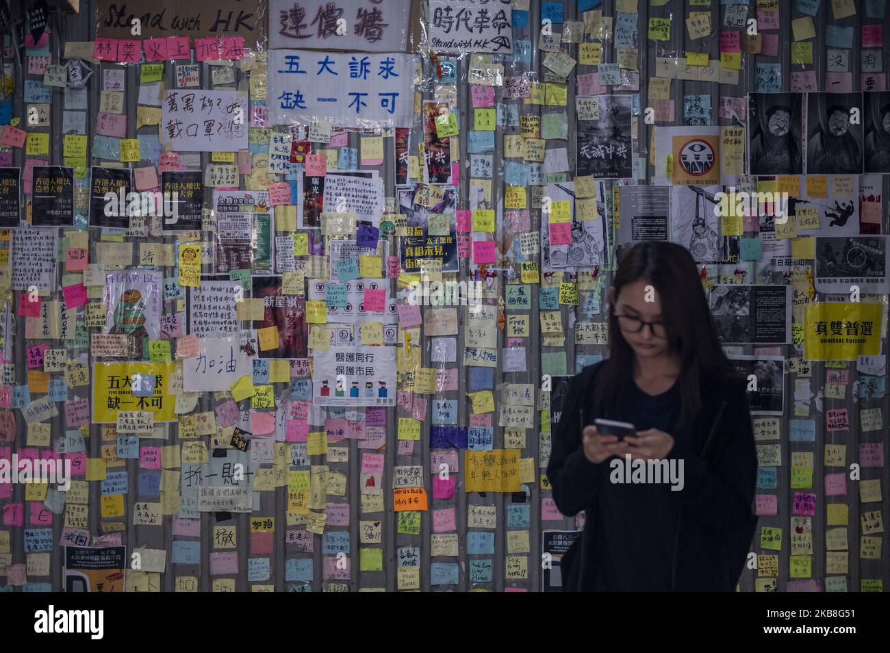 Eine Frau wird gesehen, die auf ihr Telefon schaut, während sie vor einer Lennon-Mauer in Hongkong, China, steht, 17. Oktober 2019. (Foto von Vernon Yuen/NurPhoto) Stockfoto
