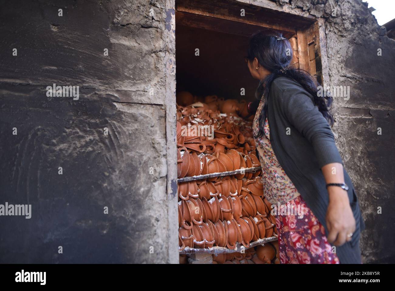 Eine Frau, die am Dienstag, den 22. Oktober 2019, Tontopf-Lampen aus dem Brennplatz für das bevorstehende Tihar- oder Deepawali-Festival auf seinem Workshop auf dem Pottery Square, Bhaktapur, Nepal, herausnimmt. Nepalese Potter arbeitet an ihrer traditionellen Töpferei in kleinem Maßstab in Bhaktapur, Nepal. Bhaktapur ist eine alte Stadt im Kathmandu Valley und wird aufgrund seiner reichen Kultur, Tempel und Holz-, Metall- und Steinkunst von der UNESCO zum Weltkulturerbe erklärt. (Foto von Narayan Maharjan/NurPhoto) Stockfoto