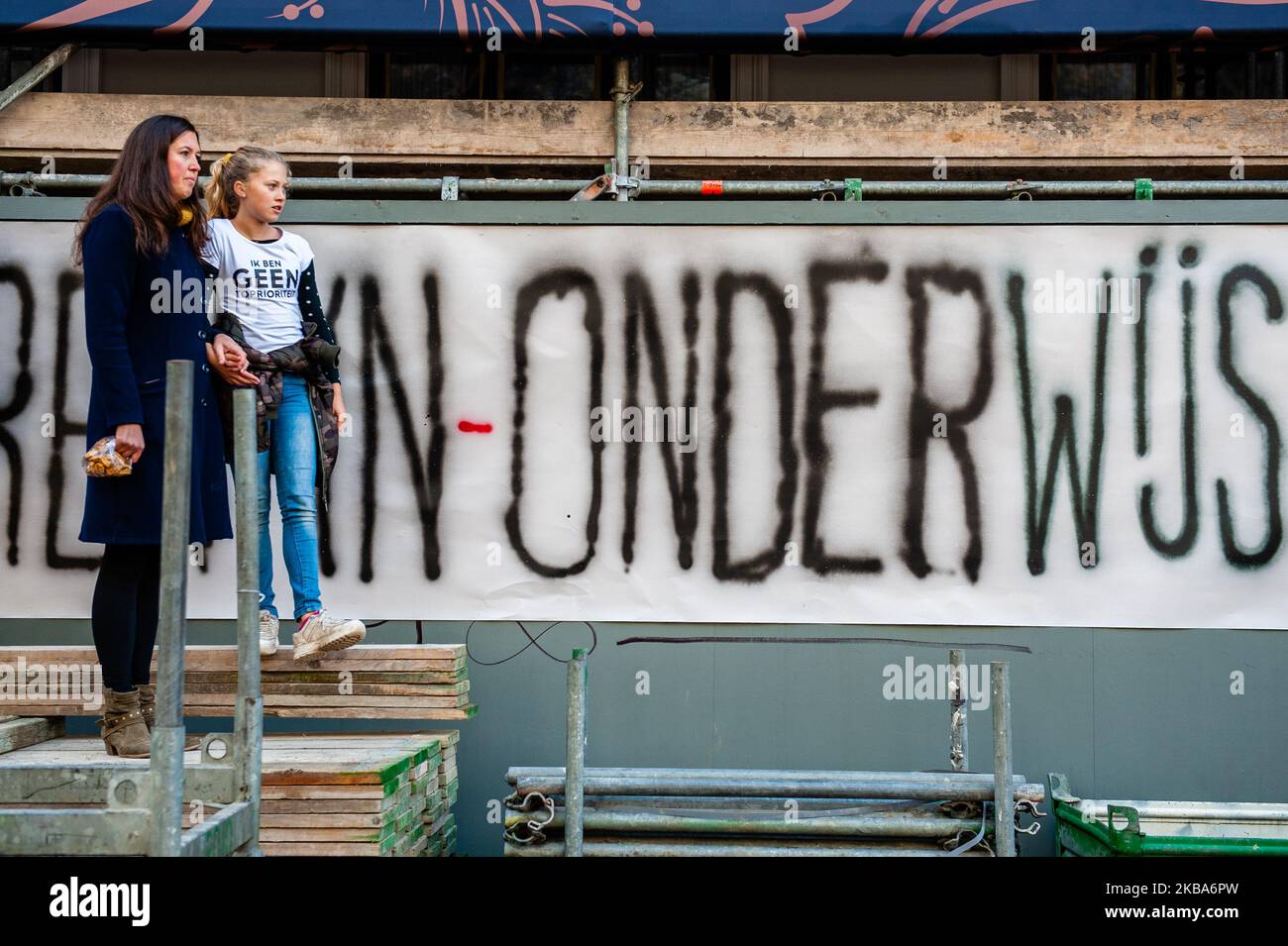 Eine Frau und ihre Tochter sind vor einem großen Banner zu sehen, auf dem das Wort Onderwijs, was Bildung auf Niederländisch bedeutet, während der massiven Lehrerdemonstration, die am 6.. November 2019 in Den Haag stattfand, rot werden kann. (Foto von Romy Arroyo Fernandez/NurPhoto) Stockfoto