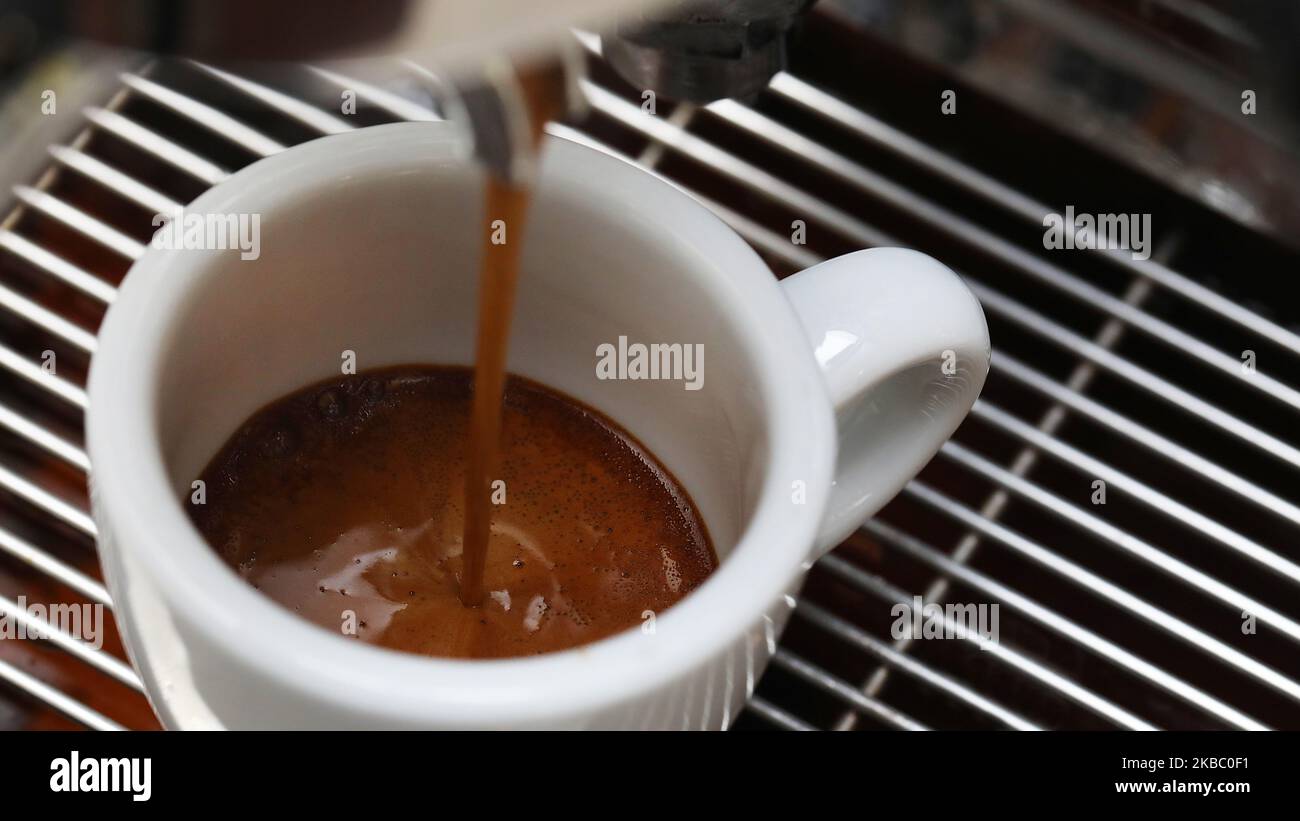 Wunderschöne extreme Makroansicht eines Espresso-Shot oder Gießen in eine kleine weiße Espresso-tulpenförmige Tasse. Barista macht den perfekten Kaffee Sho Stockfoto