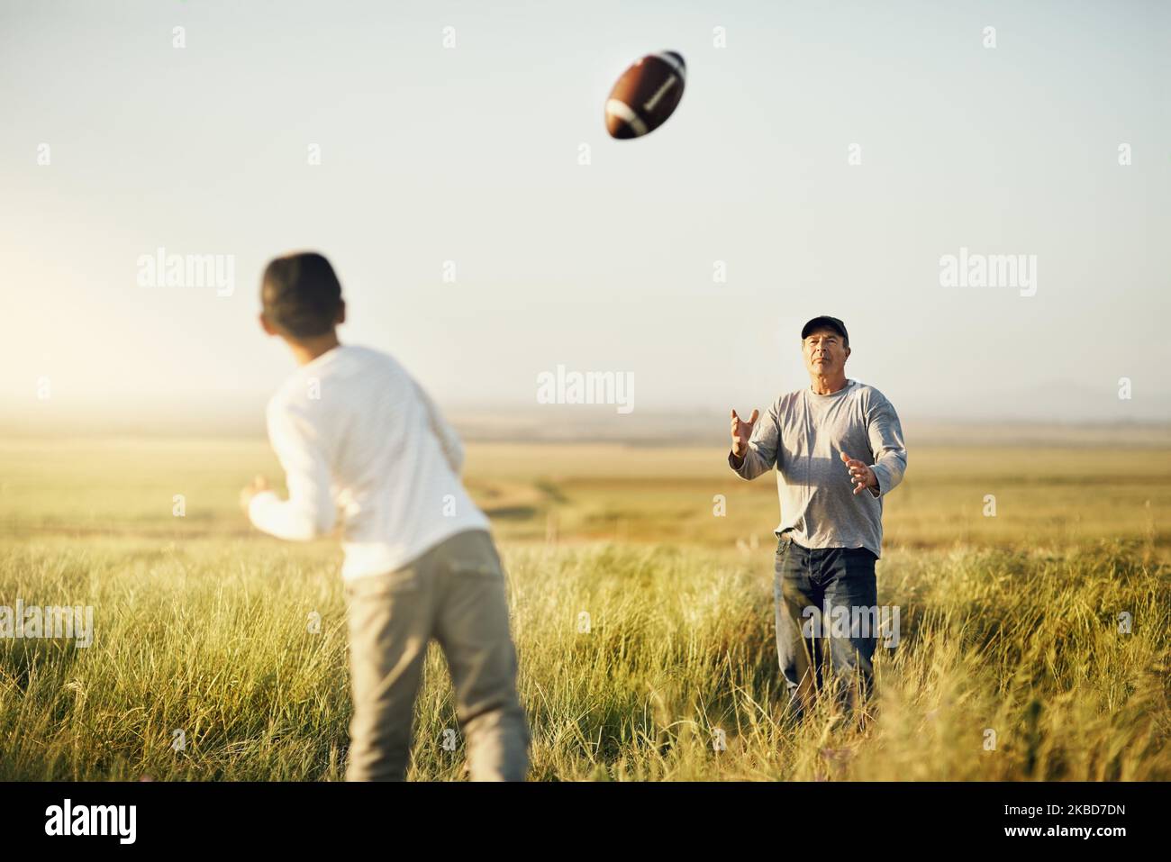 Kinder, die draußen spielen, sind körperlich aktiver. Vater und Sohn spielen Fußball auf einem offenen Feld. Stockfoto