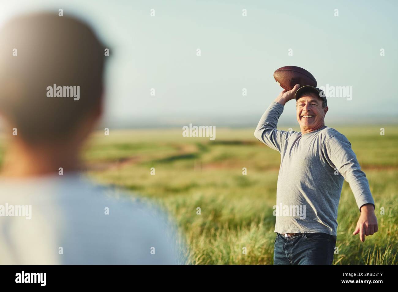 Machen Sie sich bereit, es kommt Ihren Weg. Vater wirft einen Fußball zu seinem Sohn auf einem Feld. Stockfoto
