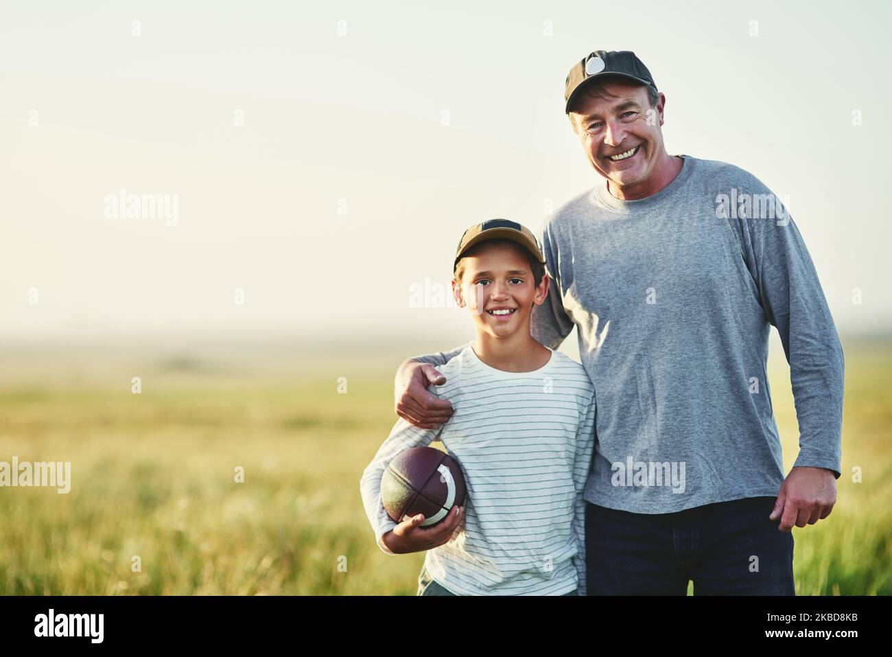 Wir beide freuen uns sehr über das Spiel. Porträt von Vater und Sohn, die mit einem Fußball auf einem Feld spielen. Stockfoto