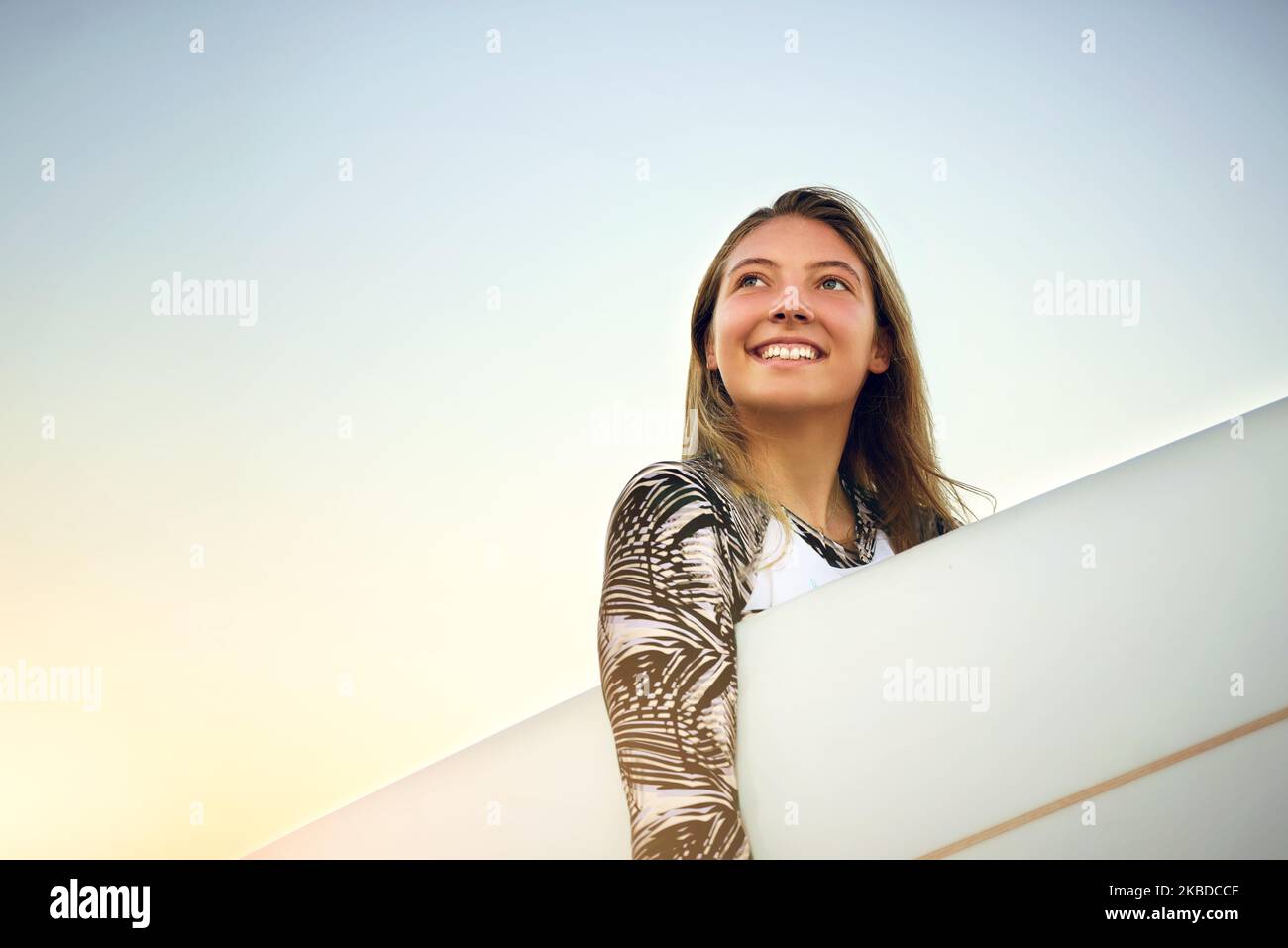 Die Geräusche des Meeres. Low-Angle-Aufnahme einer attraktiven jungen Surferin, die mit ihrem Surfbrett am Strand steht. Stockfoto