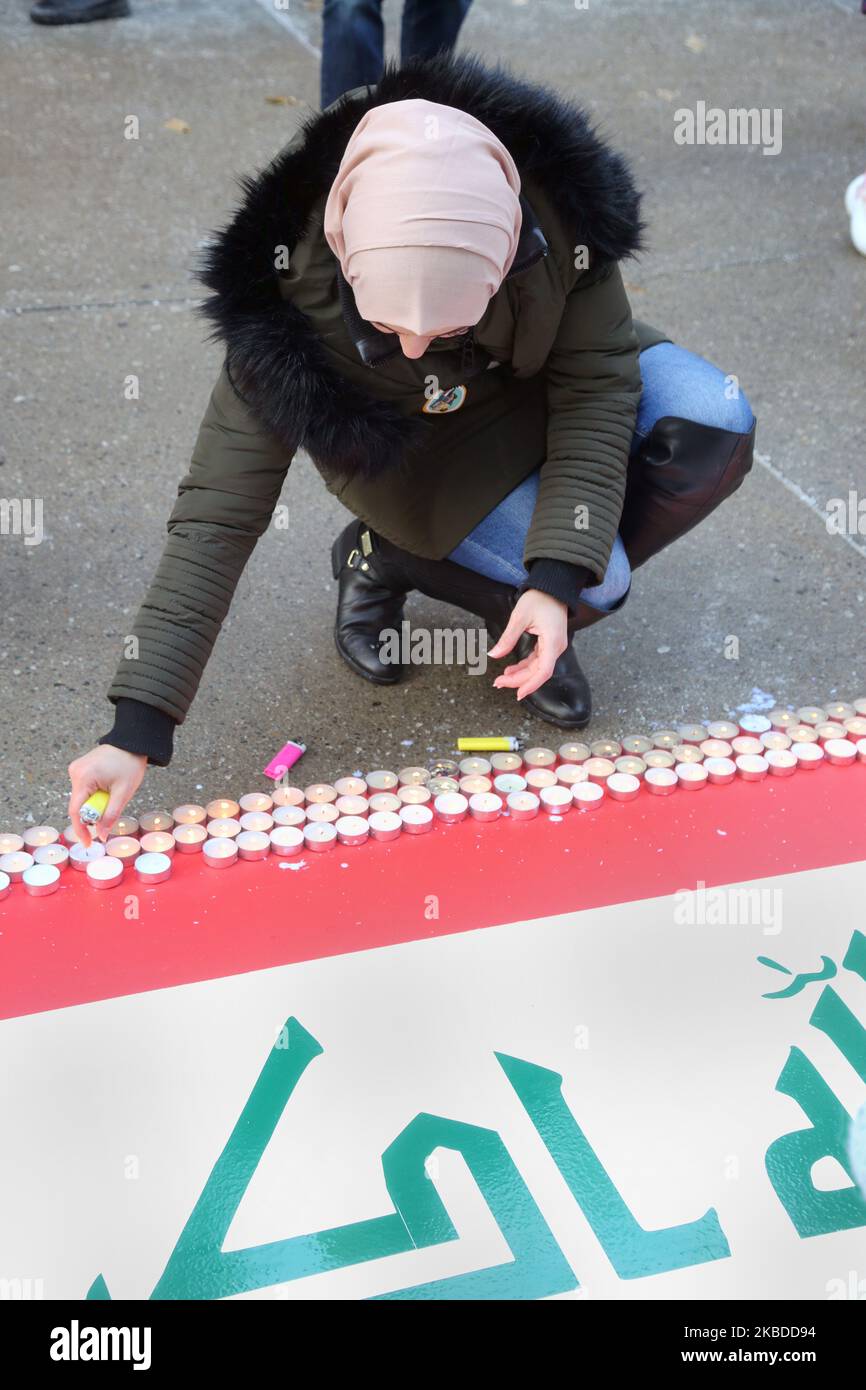 Während einer Kundgebung zur Unterstützung irakischer Demonstranten am 21. Dezember 2019 im Old City Hall in Toronto, Ontario, Kanada, zünden Menschen Kerzen an einer irakischen Flagge an. Irakische Kanadier protestierten in der Innenstadt von Toronto, um die Gewalt gegen regierungsfeindliche Demonstranten im Irak anzuprangern. Mindestens 341 Demonstranten sind seit dem 1. Oktober 2019 bei massiven Protesten im Irak ums Leben gekommen und Tausende wurden verletzt. Irakische Sicherheitskräfte feuerten Gummigeschosse und Tränengas ab, um Menschenmengen in Bagdad zu zerstreuen und dabei eine Person zu töten. Tausende Iraker demonstrieren weiterhin gegen staatliche Korruption, Wahlreformen, Arbeitslosigkeit und Stockfoto