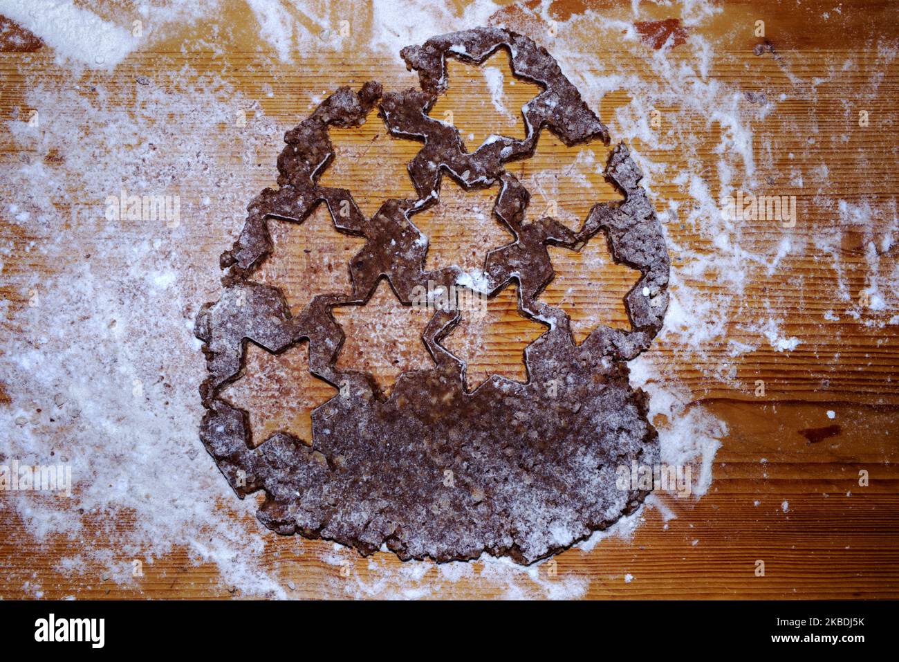 Backen von Weihnachtskandeln - Schneiden von Weihnachtskandeln aus hausgemachtem Teig in Sternformen - Zimtsterne Stockfoto