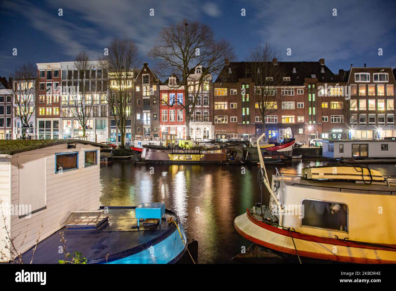 Grachten in Amsterdam wie Amstel mit typischen traditionellen alten niederländischen Architektur Häuser beleuchtet und Hausboote am Abend und Nacht mit schönen Wasserspiegelungen und Stadtlichter, Holland, Niederlande. Amsterdam ist ein Finanzzentrum, aber auch eine der meistbesuchten Städte Europas, die Millionen von Touristen auf der ganzen Welt anzieht, wobei der Tourismus eine wichtige Rolle in der lokalen Wirtschaft spielt, obwohl es Stimmen gegen diese touristische Entwicklung gibt. (Foto von Nicolas Economou/NurPhoto) Stockfoto