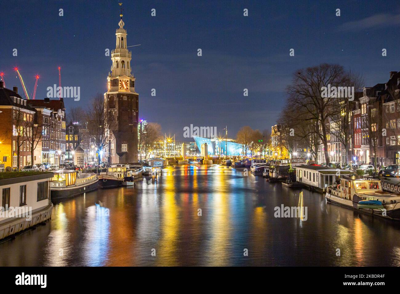 Grachten in Amsterdam wie Amstel mit typischen traditionellen alten niederländischen Architektur Häuser beleuchtet und Hausboote am Abend und Nacht mit schönen Wasserspiegelungen und Stadtlichter, Holland, Niederlande. Amsterdam ist ein Finanzzentrum, aber auch eine der meistbesuchten Städte Europas, die Millionen von Touristen auf der ganzen Welt anzieht, wobei der Tourismus eine wichtige Rolle in der lokalen Wirtschaft spielt, obwohl es Stimmen gegen diese touristische Entwicklung gibt. (Foto von Nicolas Economou/NurPhoto) Stockfoto