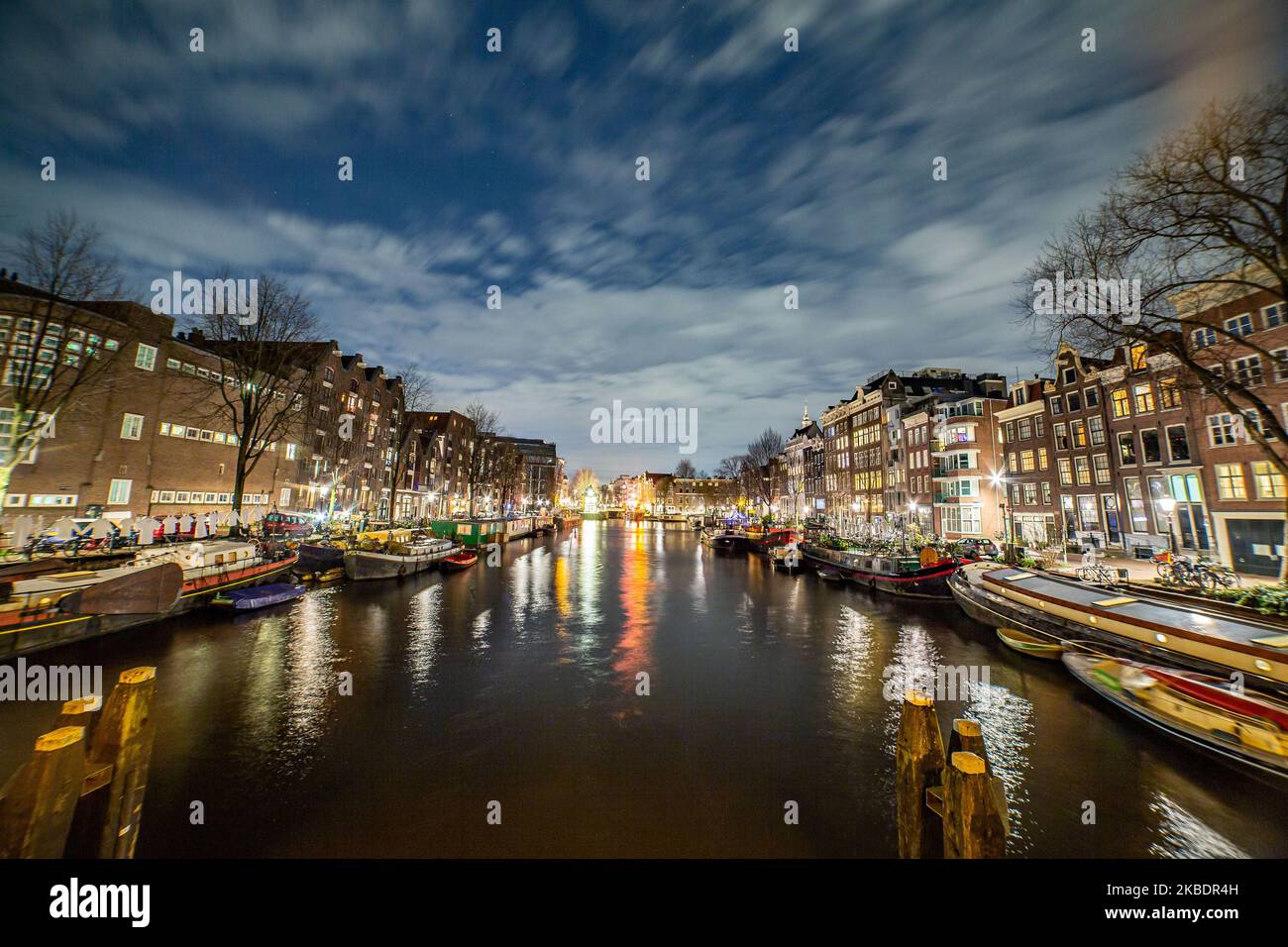 Grachten in Amsterdam wie Amstel mit typischen traditionellen alten niederländischen Architektur Häuser beleuchtet und Hausboote am Abend und Nacht mit schönen Wasserspiegelungen und Stadtlichter, Holland, Niederlande. Amsterdam ist ein Finanzzentrum, aber auch eine der meistbesuchten Städte Europas, die Millionen von Touristen auf der ganzen Welt anzieht, wobei der Tourismus eine wichtige Rolle in der lokalen Wirtschaft spielt, obwohl es Stimmen gegen diese touristische Entwicklung gibt. (Foto von Nicolas Economou/NurPhoto) Stockfoto