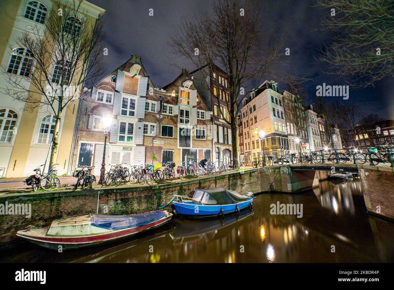 Grachten in Amsterdam wie Amstel mit typischen traditionellen alten niederländischen Architektur Häuser beleuchtet und Hausboote am Abend und Nacht mit schönen Wasserspiegelungen und Stadtlichter, Holland, Niederlande. Amsterdam ist ein Finanzzentrum, aber auch eine der meistbesuchten Städte Europas, die Millionen von Touristen auf der ganzen Welt anzieht, wobei der Tourismus eine wichtige Rolle in der lokalen Wirtschaft spielt, obwohl es Stimmen gegen diese touristische Entwicklung gibt. (Foto von Nicolas Economou/NurPhoto) Stockfoto