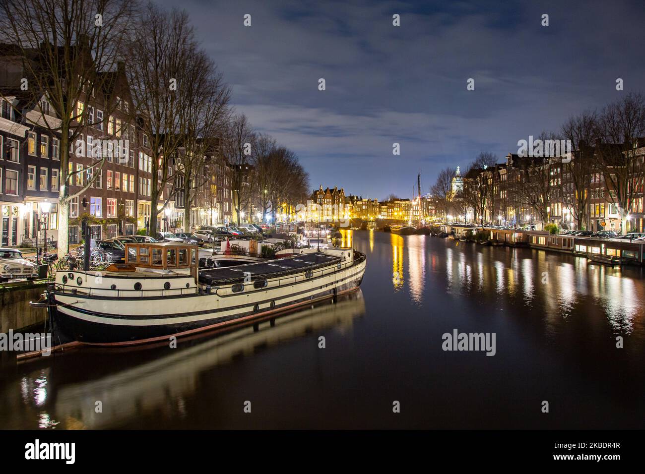 Grachten in Amsterdam wie Amstel mit typischen traditionellen alten niederländischen Architektur Häuser beleuchtet und Hausboote am Abend und Nacht mit schönen Wasserspiegelungen und Stadtlichter, Holland, Niederlande. Amsterdam ist ein Finanzzentrum, aber auch eine der meistbesuchten Städte Europas, die Millionen von Touristen auf der ganzen Welt anzieht, wobei der Tourismus eine wichtige Rolle in der lokalen Wirtschaft spielt, obwohl es Stimmen gegen diese touristische Entwicklung gibt. (Foto von Nicolas Economou/NurPhoto) Stockfoto