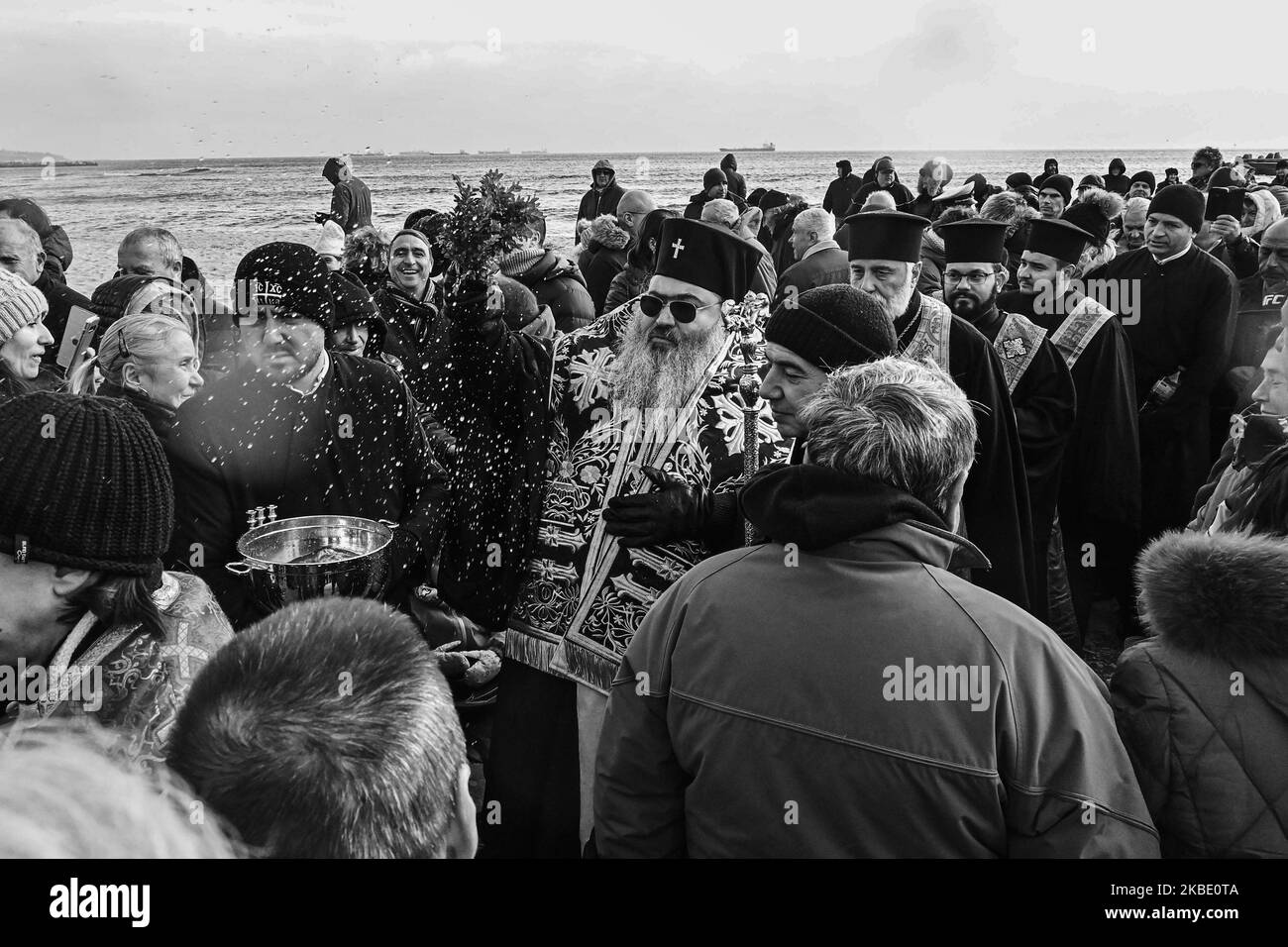 (ANMERKUNG DER REDAKTION: Bild wurde in Schwarz-Weiß umgewandelt) Bulgaren feiern die Epiphanie, als Männer im frostigen Wasser des Schwarzen Meeres bei der so genannten Zeremonie „das Kreuz aus dem Meer nehmen“ am 6. Januar 2020 in Varna, Bulgarien, springen. Traditionell wirft ein orthodoxer Priester ein Kreuz in den Fluss und es wird angenommen, dass derjenige, der es holt, das ganze Jahr über gesund sein wird, sowie alle, die im eisigen Wasser tanzen. (Foto: Impact Press Group/NurPhoto) Stockfoto
