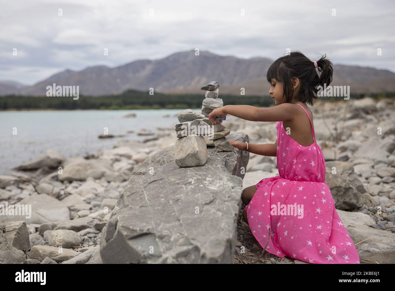 Ein kleines Mädchen versucht am 10. Januar 2020 am See TekapoÂ auf der zentralen Südinsel von New ZealandÂ eine temporäre Skulptur aus Steinen zu schaffen.Â Tekapo ist eine der beliebtesten Touristenattraktionen Neuseelands.Â Â (Foto: Sanka Vidanagama/NurPhoto) Stockfoto