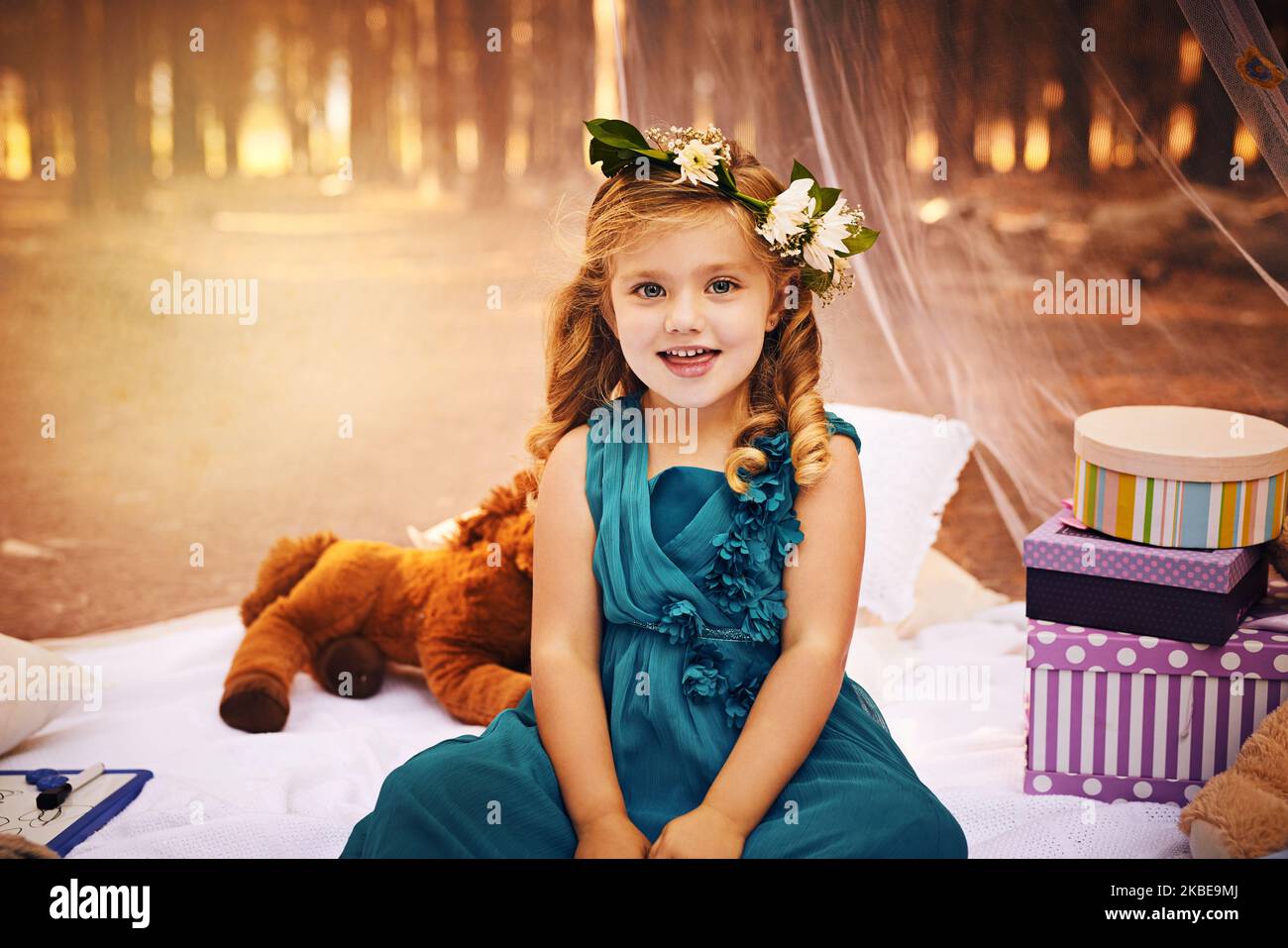 Shes in ihrem Element. Ein glückliches kleines Mädchen, das auf die Kamera schaut, während es draußen auf einer Decke im Wald sitzt. Stockfoto