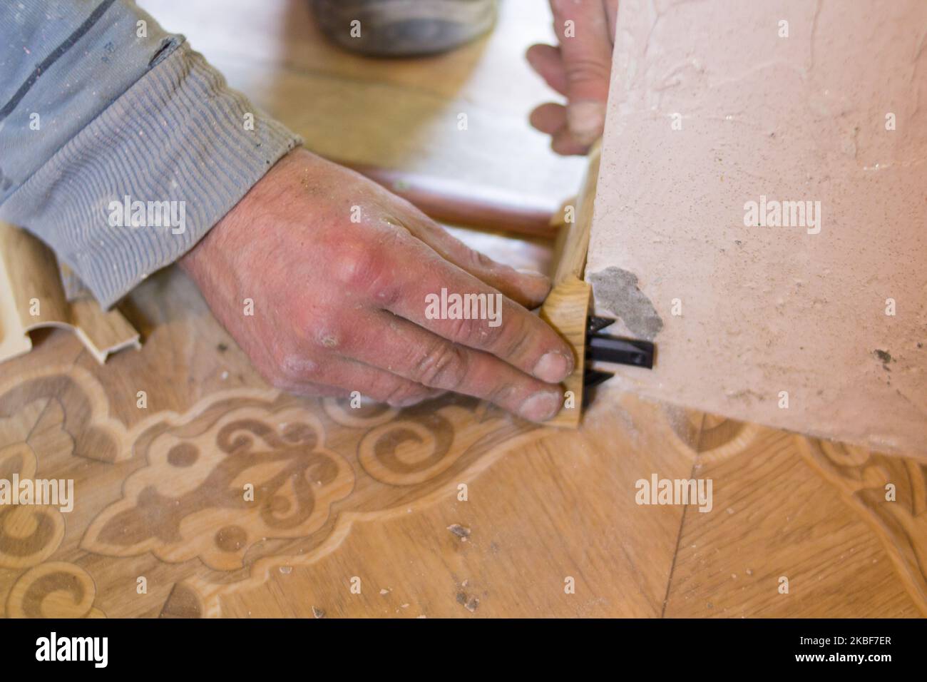 Junger Arbeiter in Uniform Installation neuer Baseboard zu Hause Stockfoto