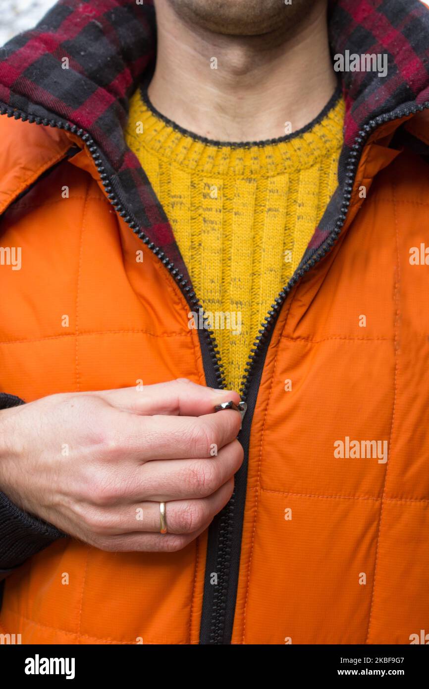 Ein Mann mit Winterjacke trägt einen Verschluss Stockfoto