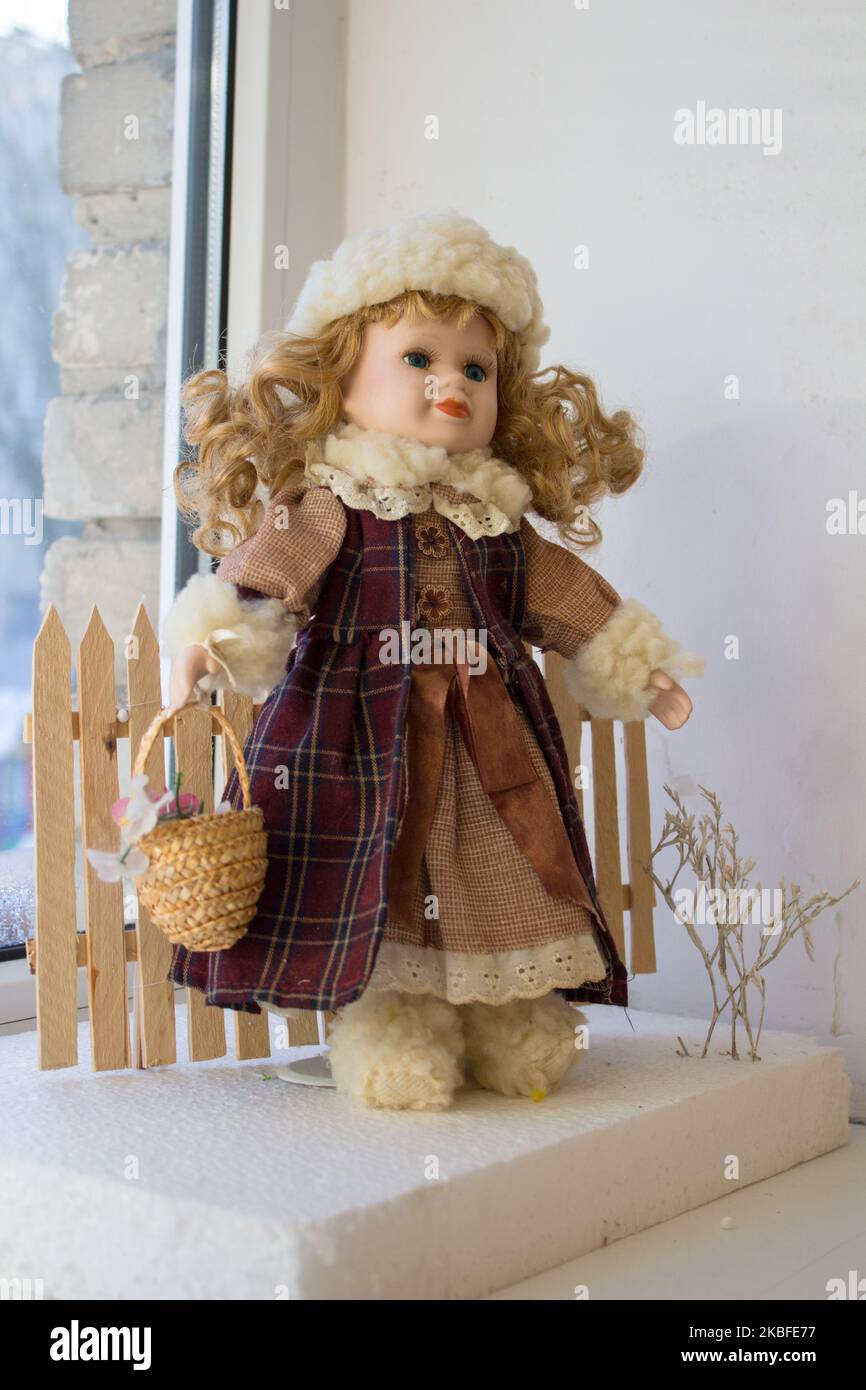 Schöne Puppe im Wintermantel mit Korb Stockfoto