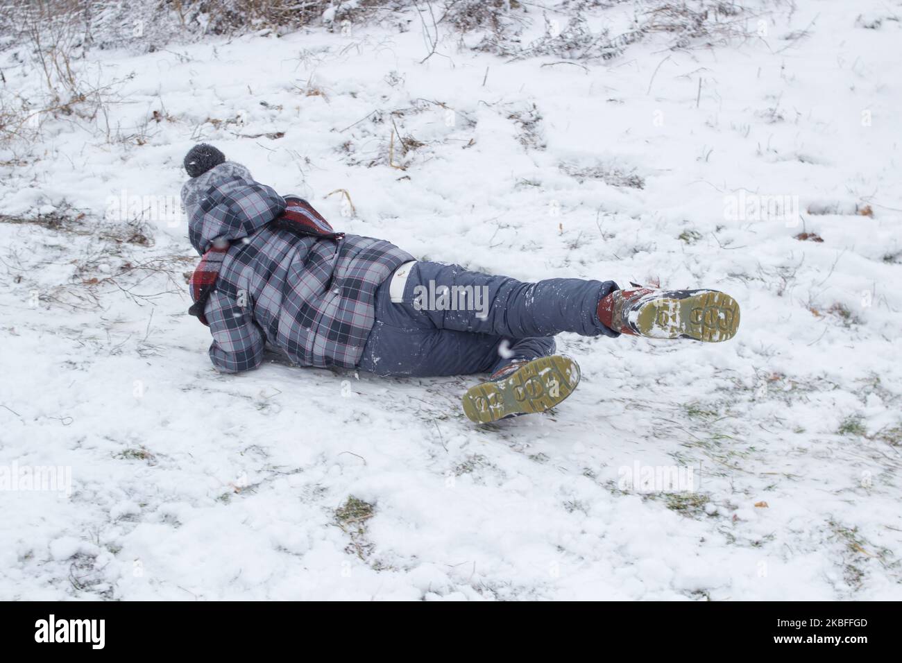 Versehentlich fiel ein kleiner Junge auf den Schnee Stockfoto