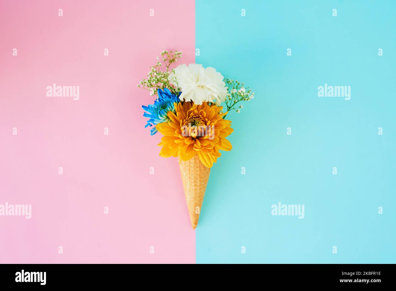 Fügen Sie einfach Blumen. Ein Kegel mit Blumen vor einem bunten Hintergrund gefüllt. Stockfoto