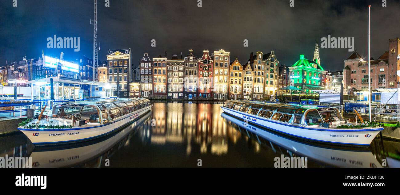 Die berühmten bunten Tanzhäuser mit authentischer holländischer Architektur säumen traditionelle Gebäude mit Lichtern. Die beleuchteten Häuser über dem Wasser am Damrak-Kanal-Becken sind eine berühmte Touristenattraktion, ein Wahrzeichen in der Nähe des Hauptbahnhofs, eine wichtige Touristenattraktion, in Amsterdam, Holland, den Niederlanden, wie sie nach Sonnenuntergang, während der magischen blauen Stunde, Dämmerung und Nacht gesehen werden. Amsterdam, Niederlande (Foto von Nicolas Economou/NurPhoto) Stockfoto
