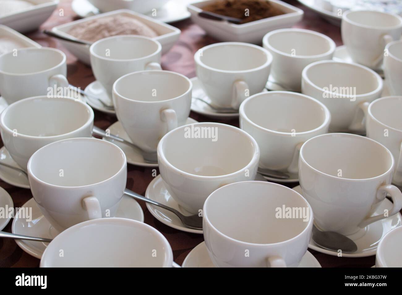 Viele weiße Kaffeetassen in einer Reihe über einem Buffet Stockfoto