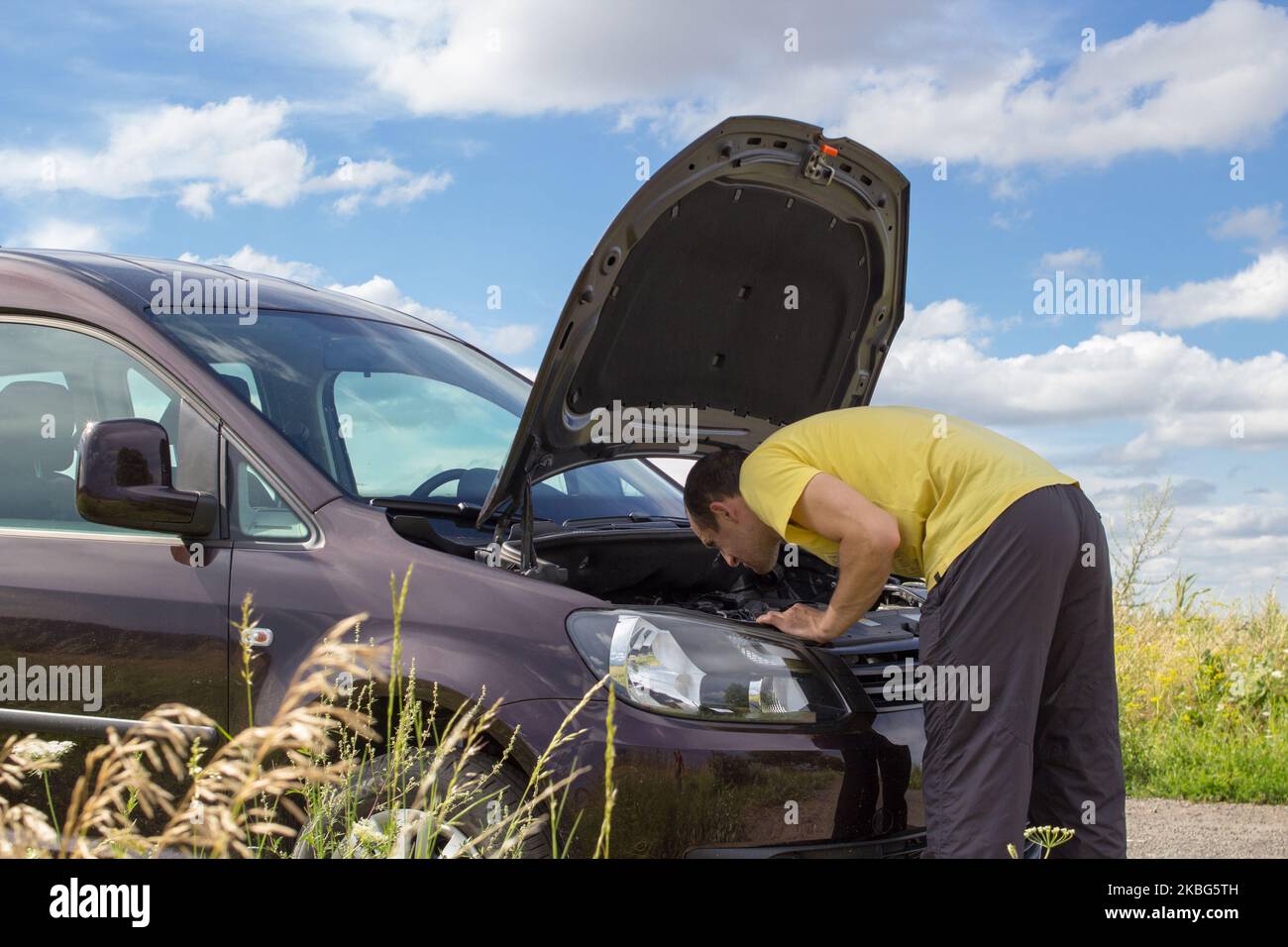 Ein Mann auf der Straße repariert ein Auto unter der Haube Stockfoto