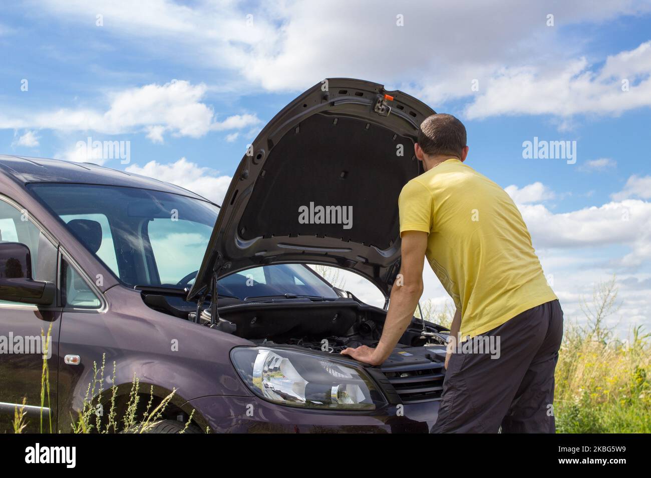 Im Sommer wurde ein Auto von einem Mann in der Nähe der offenen Motorhaube eines Autos gebrochen Stockfoto