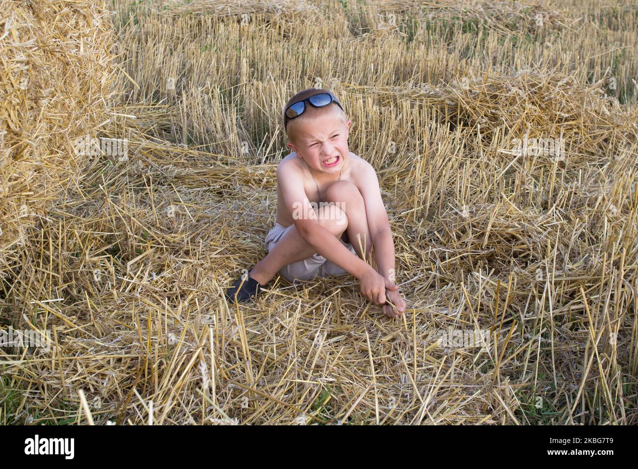 Der Junge saß emotional im quadratischen Weizenfeld Stockfoto