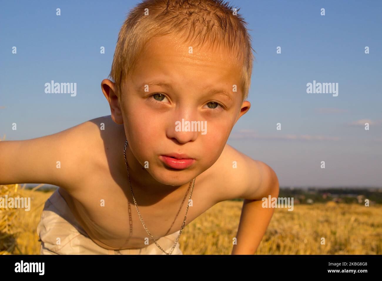 Ein lustiger Junge, der bei Sonnenuntergang in die Kamera schaut Stockfoto