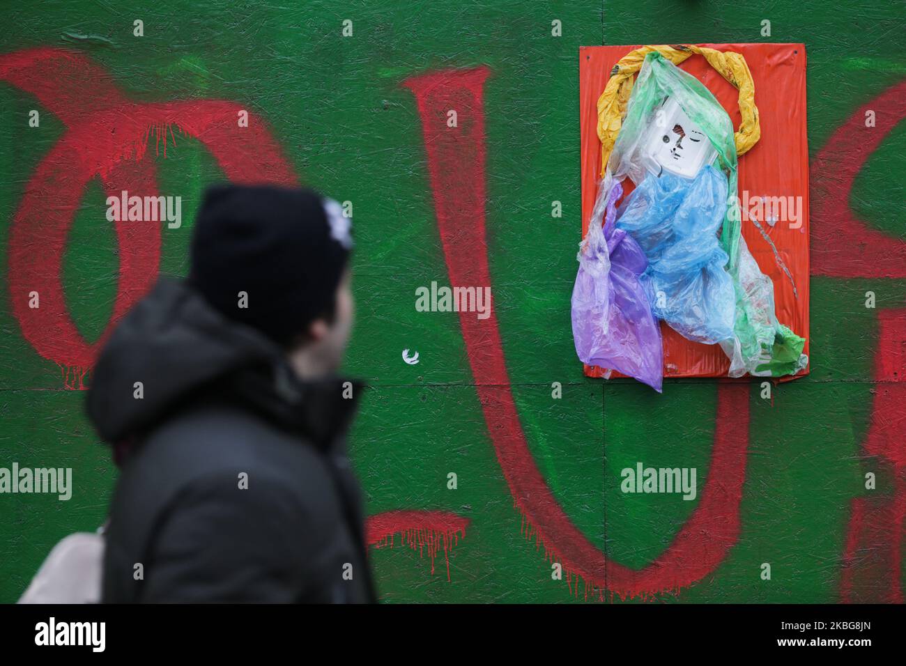 Ein Mann geht am Kunstobjekt der PlasticWood-Gruppe vorbei, das am Bauzaun in Kiew, Ukraine, am 4. Februar 2020 hängt. Die ukrainische Öko-Kunstgruppe PlasticWood kreiert die Kunstobjekte aus den Abfällen und hängt sie in der Innenstadt von Kiew auf. (Foto von Sergii Chartschenko/NurPhoto) Stockfoto