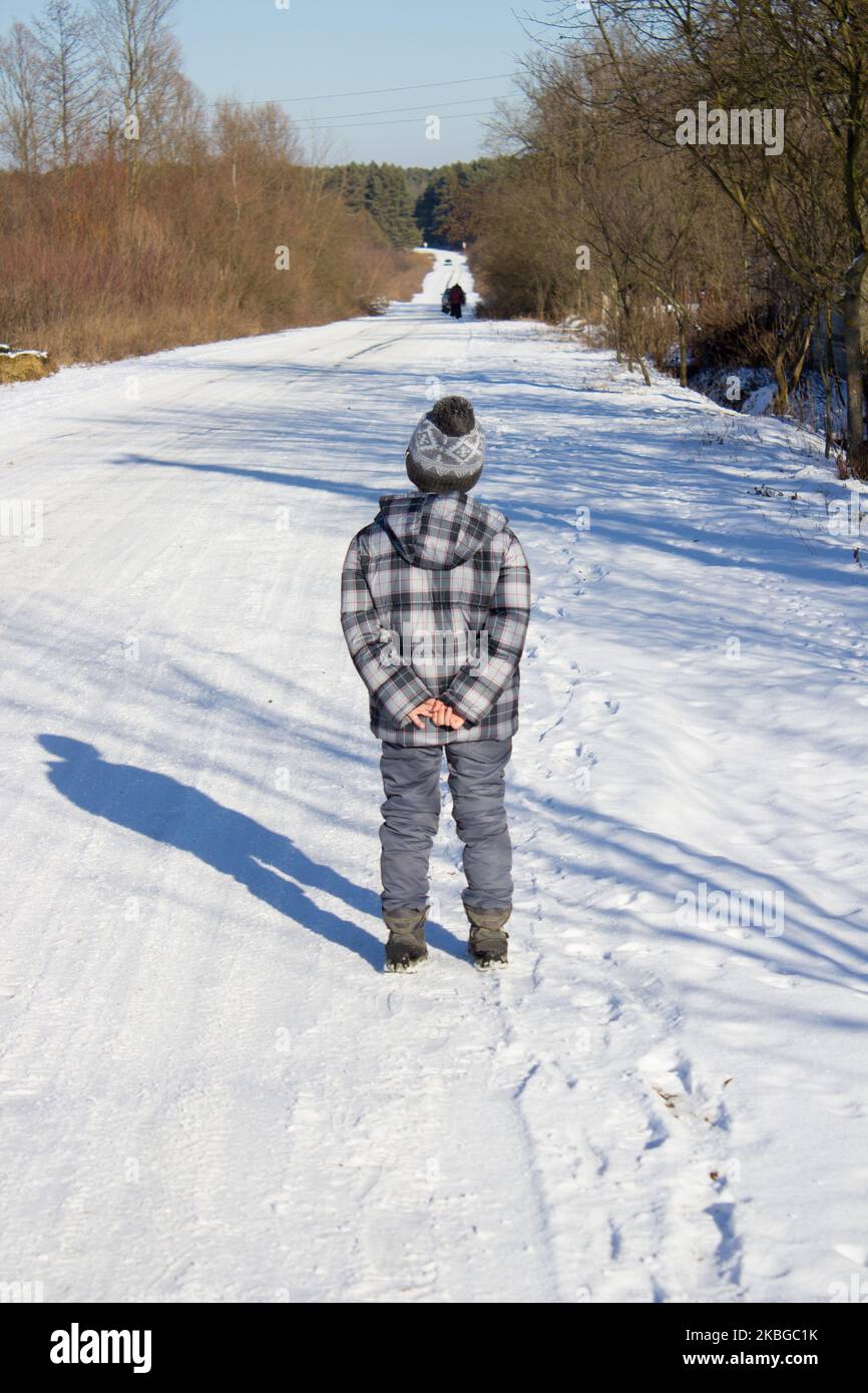 Junge steht im Winter auf der Straße zurück Stockfoto