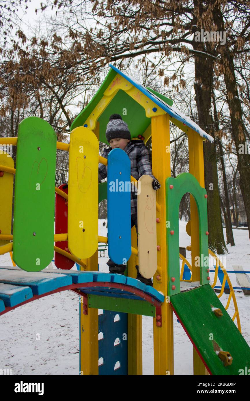 Spielen Winter im Park auf Kinderrutschen kleiner Junge Stockfoto