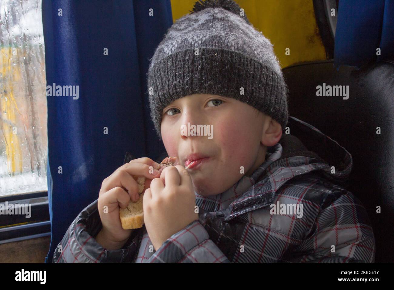 Porträt eines Jungen, der im Auto des Winters Sandwiches isst Stockfoto