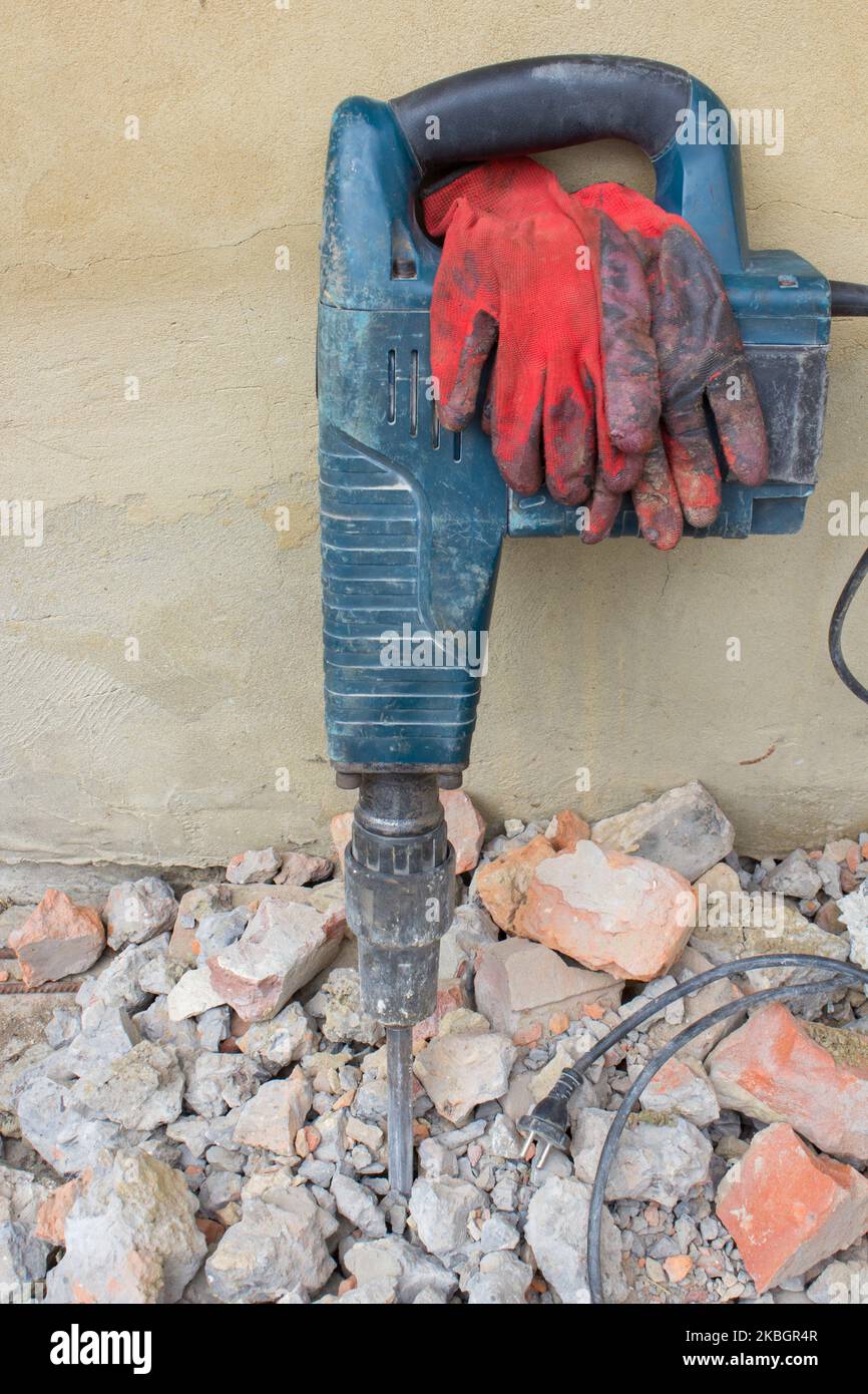 Hand-Werkzeug-Elektrostanzer auf einem Stein in der Nähe der Wand Stockfoto