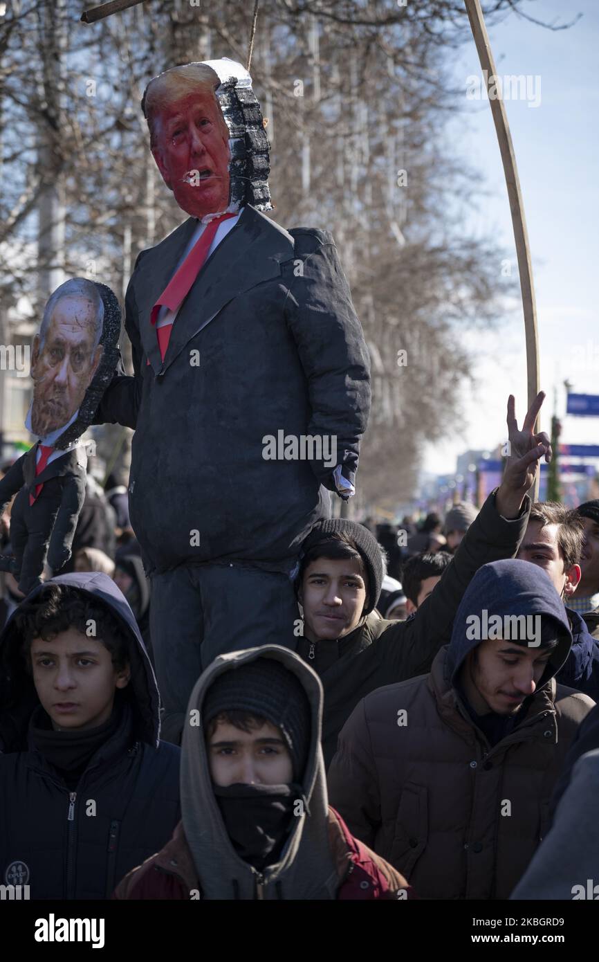 Ein iranischer Schuljunge blitzen ein Siegeszeichen auf, während er am 11. Februar 2020 auf dem Azadi-Platz (Freiheit) im Westen Teherans einen hingerichteten US-Präsidenten Donald Trump und ein Bildnis des israelischen Premierministers Benjamin Netanjahu bei einer Kundgebung zum Jahrestag der Islamischen Revolution trägt. - Tausende von Iranern, die sich zum Gedenken an die 41 Jahre seit der Islamischen Revolution zusammenschlossen, in einer Zeit erhöhter Spannungen mit den Vereinigten Staaten, als Zeichen der Einheit. Die Feierlichkeiten markieren den Tag, an dem der schiitische Geistliche Khomeini aus dem Exil zurückkehrte und die letzte Regierung des schahs verdrängte. (Foto von Morteza Stockfoto