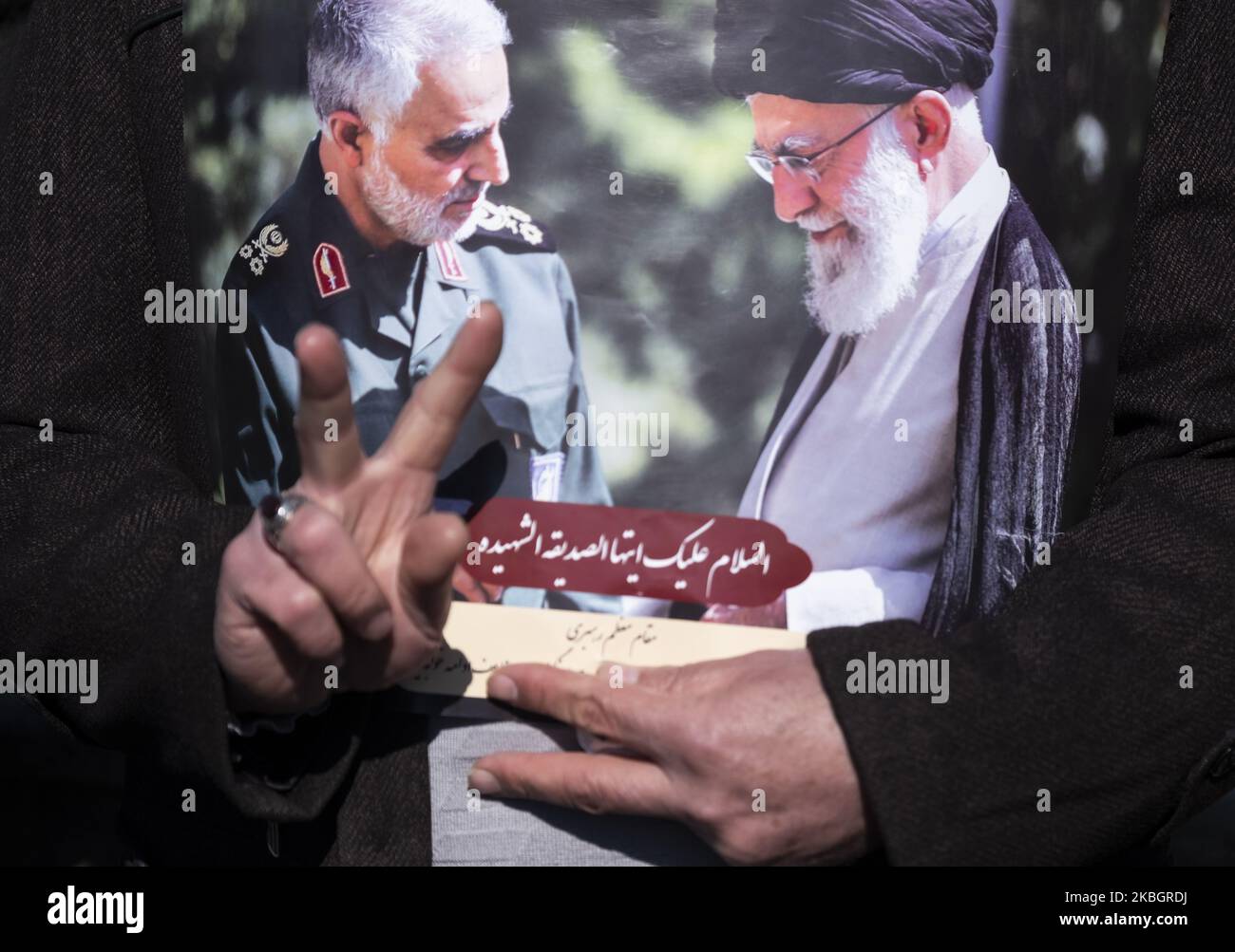 Ein Iraner zeigt ein Siegeszeichen, während er ein Plakat mit Bildern des iranischen Obersten Führers Ayatollah Ali Khamenei (R) und des ehemaligen Korps der islamischen Revolutionsgarden Qasem Soleimani hält. Während einer Kundgebung anlässlich des Jahrestages der Islamischen Revolution am 11. Februar 2020 auf dem Azadi-Platz (Freiheit) im Westen Teherans. - Tausende von Iranern, die sich zum Gedenken an die 41 Jahre seit der Islamischen Revolution zusammenschlossen, in einer Zeit erhöhter Spannungen mit den Vereinigten Staaten, als Zeichen der Einheit. Die Feierlichkeiten markieren den Tag, an dem der schiitische Khomeini aus dem Exil zurückkehrte und die shah's la verdrängte Stockfoto