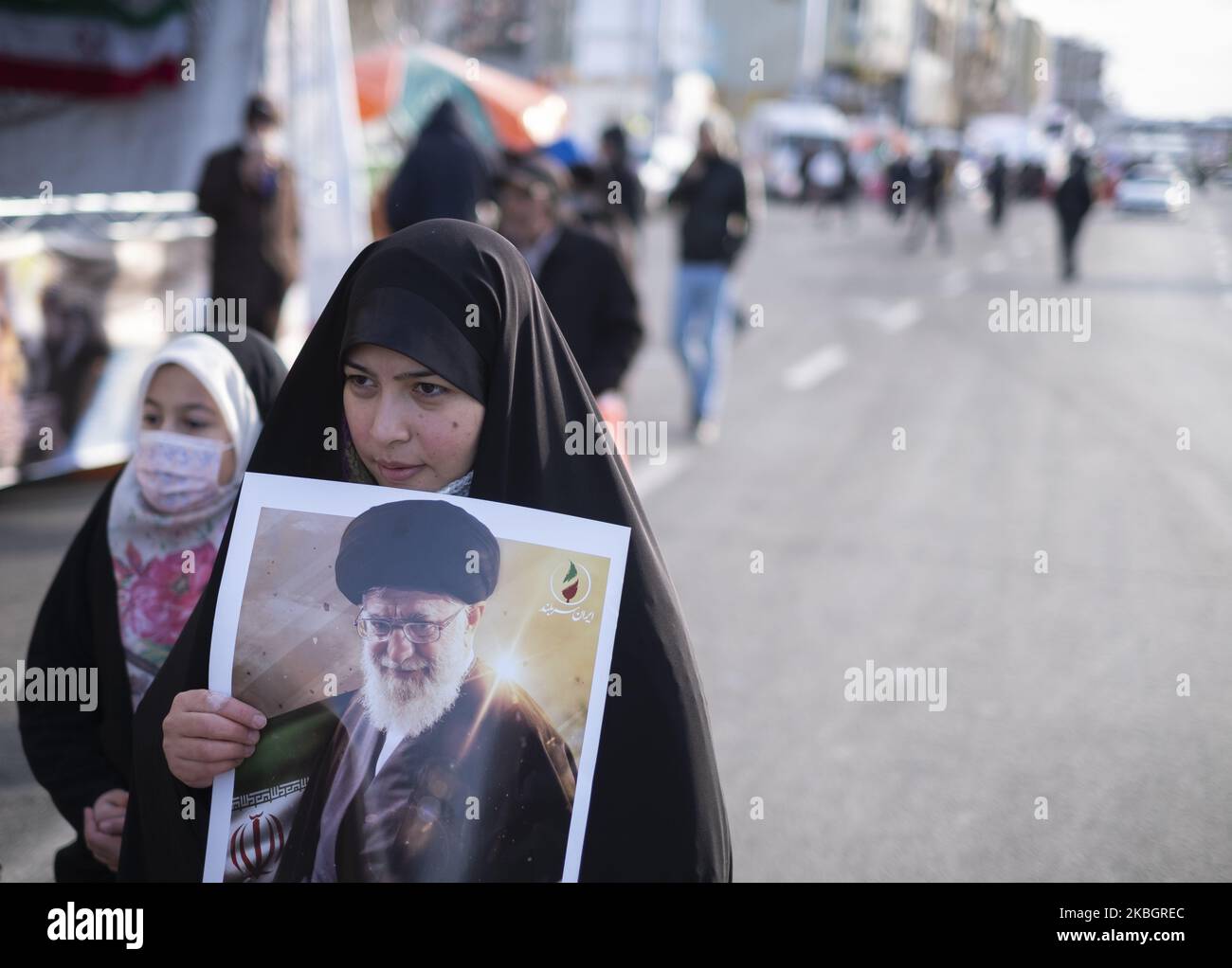 Eine verschleierte iranische Frau geht entlang der Azadi (Freedom) Avenue, während sie ein Porträt des iranischen Obersten Führers Ayatollah Ali Khamenei während einer Kundgebung anlässlich des Jahrestages der Islamischen Revolution im Westen Teherans am 11. Februar 2020 trägt. - Tausende von Iranern, die sich zum Gedenken an die 41 Jahre seit der Islamischen Revolution zusammenschlossen, in einer Zeit erhöhter Spannungen mit den Vereinigten Staaten, als Zeichen der Einheit. Die Feierlichkeiten markieren den Tag, an dem der schiitische Geistliche Khomeini aus dem Exil zurückkehrte und die letzte Regierung des schahs verdrängte. (Foto von Morteza Nikoubazl/NurPhoto) Stockfoto