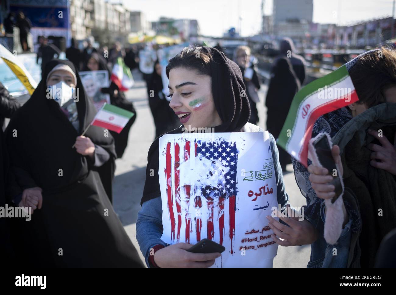Eine Iranerin geht auf der Azadi (Freedom) Avenue entlang, während sie während einer Kundgebung zum Jahrestag der Islamischen Revolution im Westen Teherans am 11. Februar 2020 ein Plakat gegen die USA trägt. - Tausende von Iranern, die sich zum Gedenken an die 41 Jahre seit der Islamischen Revolution zusammenschlossen, in einer Zeit erhöhter Spannungen mit den Vereinigten Staaten, als Zeichen der Einheit. Die Feierlichkeiten markieren den Tag, an dem der schiitische Geistliche Khomeini aus dem Exil zurückkehrte und die letzte Regierung des schahs verdrängte. (Foto von Morteza Nikoubazl/NurPhoto) Stockfoto