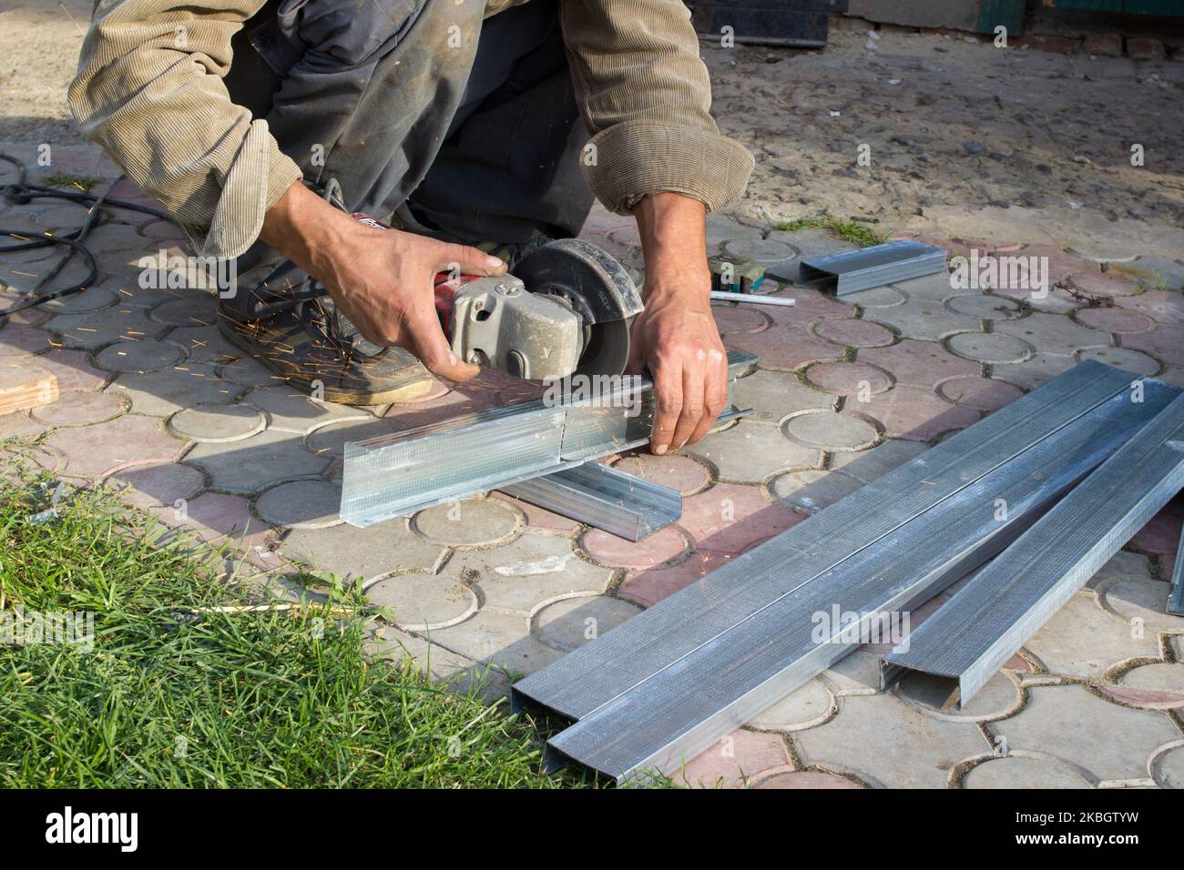 Ein man Cut Winkelschleifer ein Metallprofil für Trockenbau, das ein Metallprofil führt Stockfoto