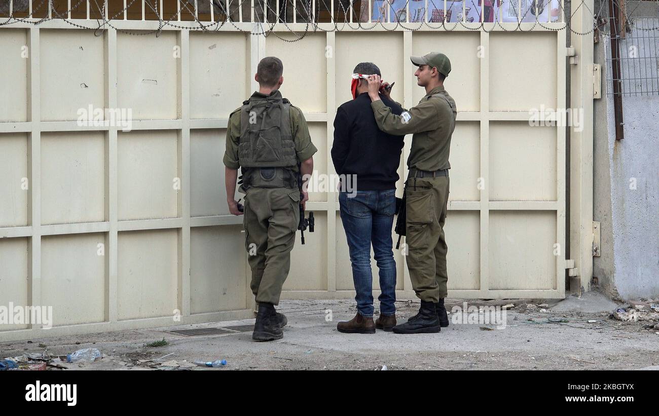 Israelischer Soldat steht mit verbundenen Augen und Handschellen an einem geschlossenen Metalltor, das die israelische Siedlung Beit Hadassah von der Zone H1 trennt, in der die meisten palästinensischen Bewohner von Hebron am 30. Oktober 2022 in Hebron, Israel, leben. Stockfoto