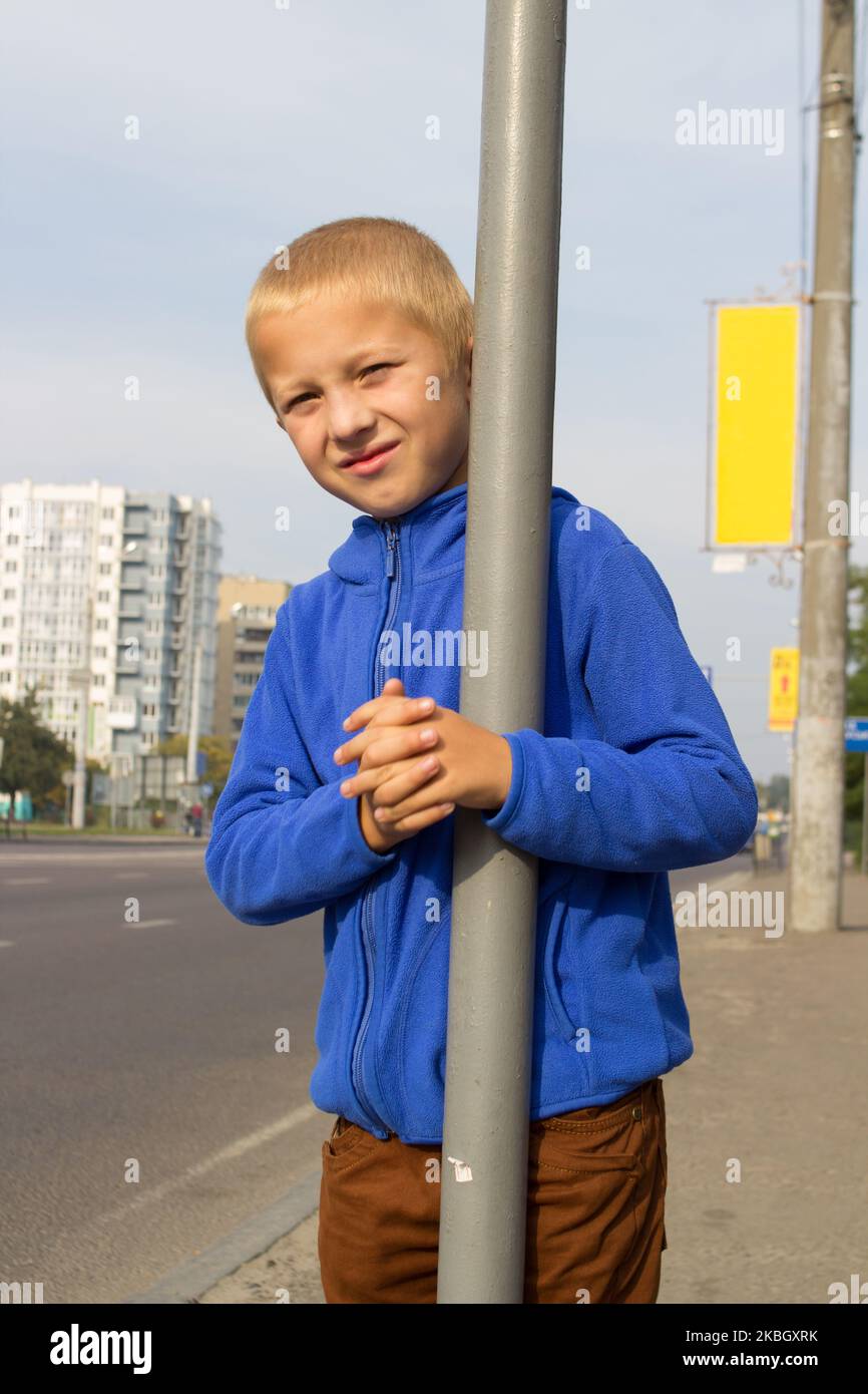 Der Junge umarmte die Metallsäule neben der Straße Stockfoto