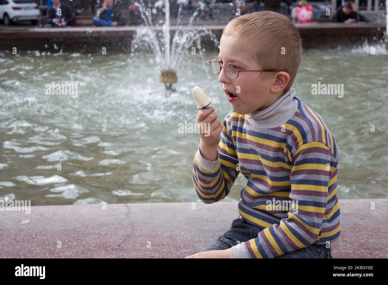 Junge mit offenem Mund isst Eis Stockfoto