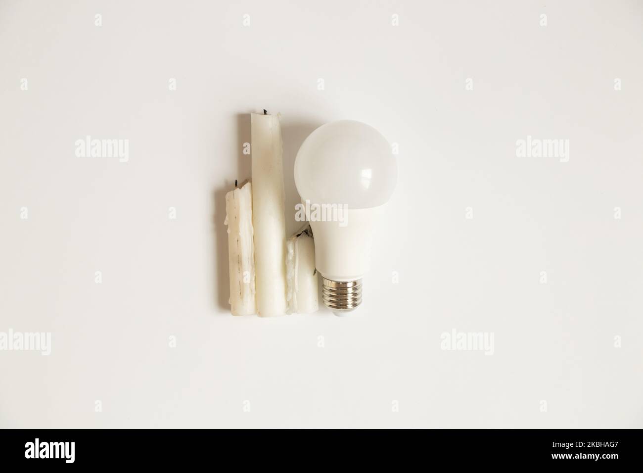 LED-Glühbirne und Kerzen auf weißem Hintergrund, Wahl der Elektrizität und Einsparungen, kein Licht Stockfoto