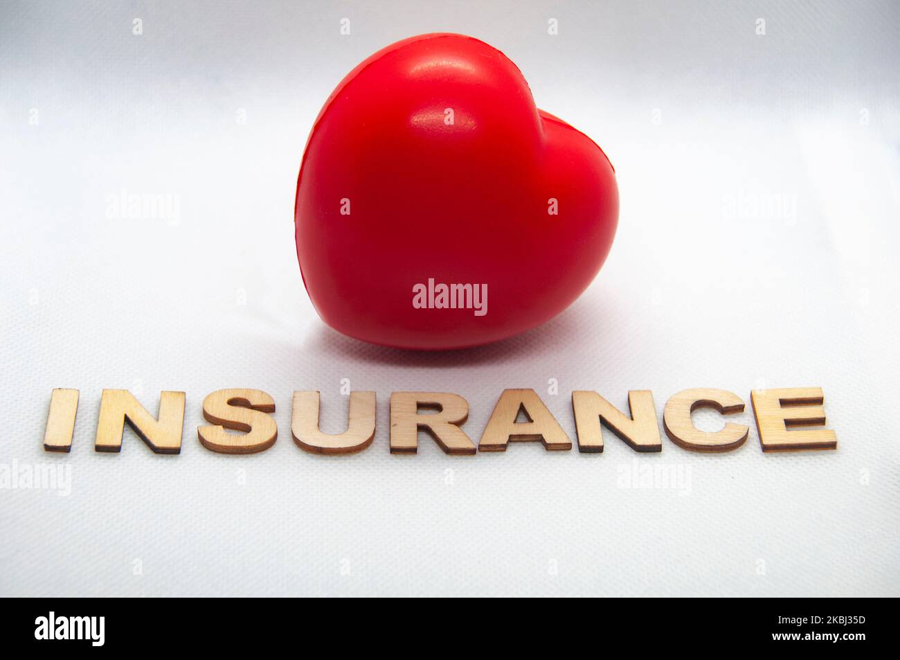 Versicherungstext aus Holz mit roter Herzform auf weißem Hintergrund. Lebensversicherung und Sicherheitskonzept. Stockfoto