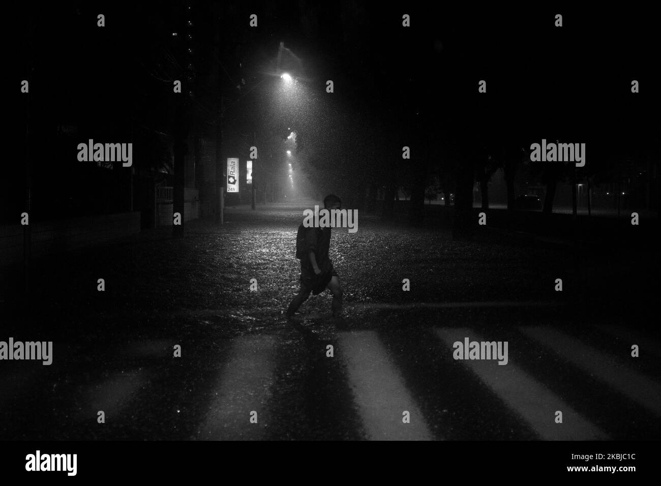 (ANMERKUNG DES HERAUSGEBERS: Bild wurde in Schwarz-Weiß umgewandelt) Ein Mann, der mitten in der Flut auf der Avenida Washington Luiz (Kanal 03) in Santos, Sao Paulo, Brasilien, in der Nacht des 2. März 2020 den Fußgängerüberweg überquerte. (Foto von: Stockfoto
