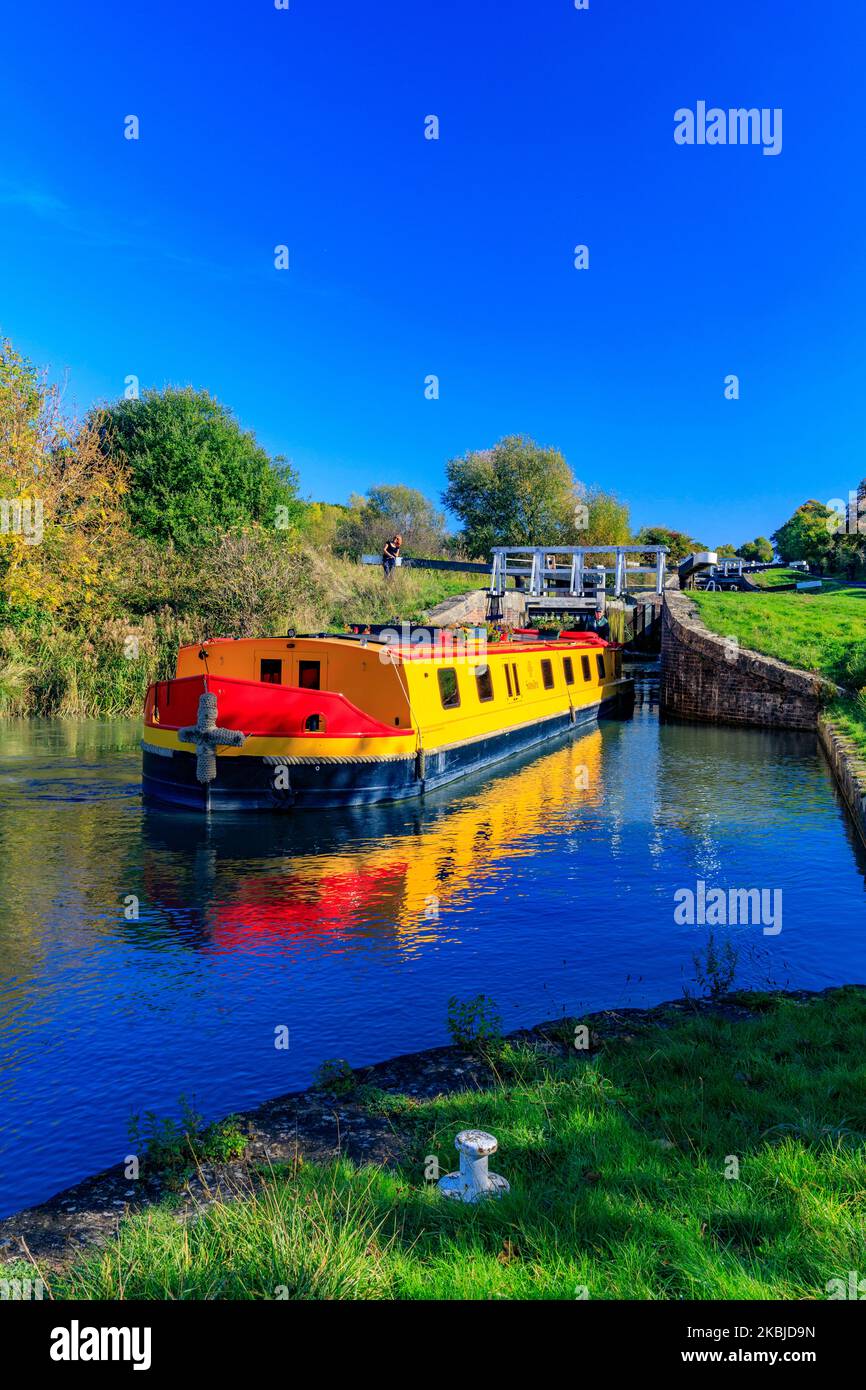 Ein farbenprächtiges Kanalboot mit breiten Balken, das im Herbst auf dem Kennet & Avon Canal, bei Devizes, Wiltshire, England, eine der 29 Schleusen in Caen Hill ausfährt Stockfoto