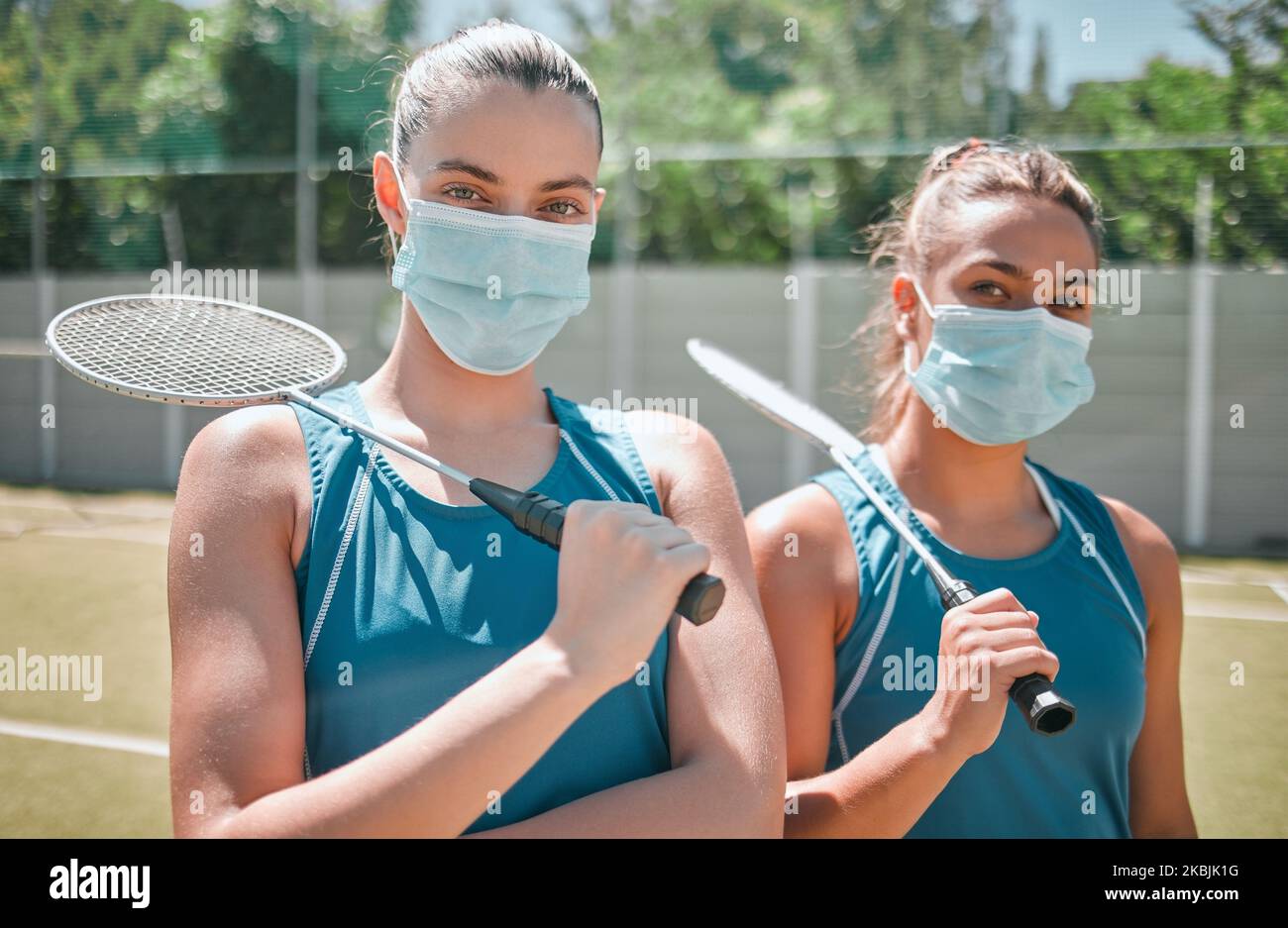 Covid Maske, Badminton und Frauen Sport Duo bereit für ein Sportspiel, Spiel und Outdoor-Platz. Portrait einer weiblichen Mannschaft in der Sonne zusammen mit einem Schläger Stockfoto