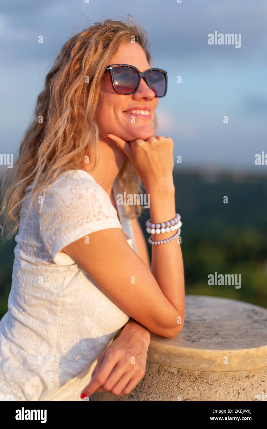 Junge, positive kaukasische Frau in Sonnenbrillen, die den Sonnenuntergang im Freien genießen Stockfoto